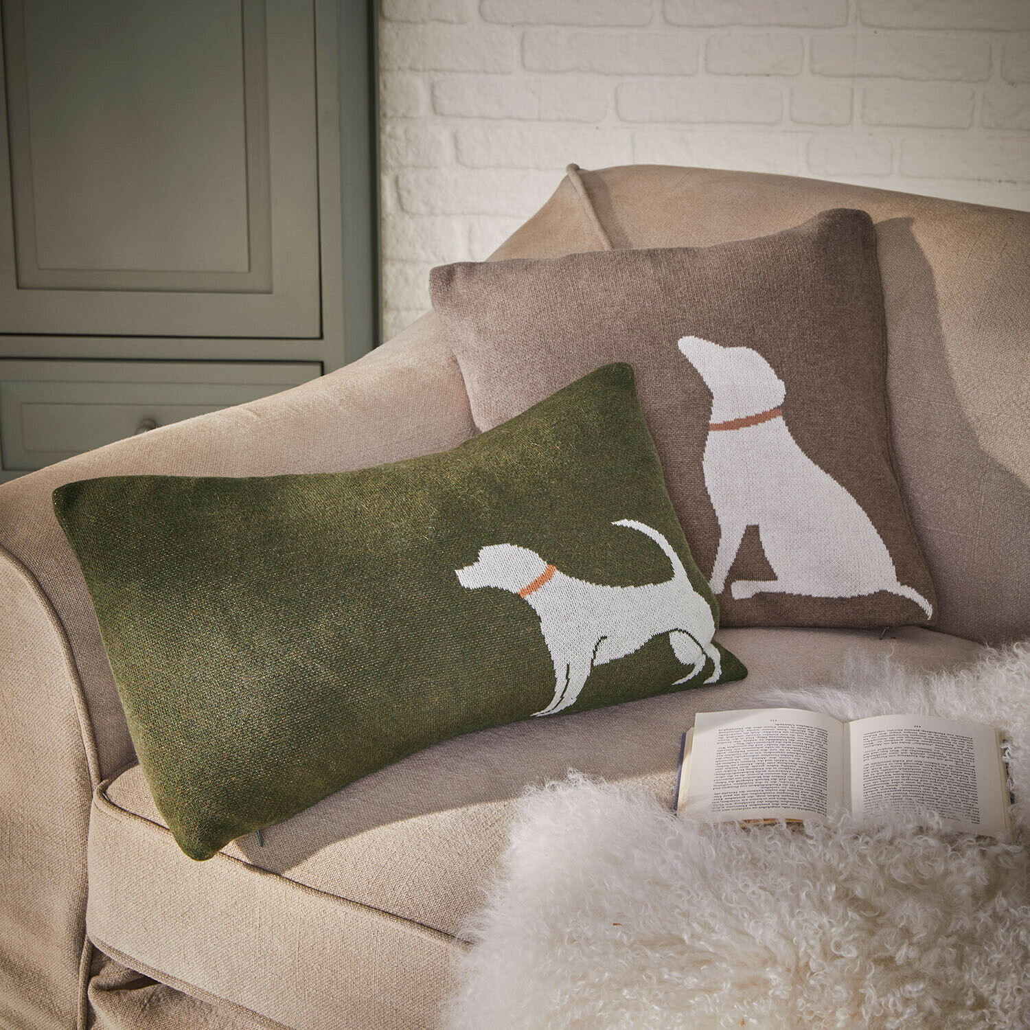 Lot de 2 housses de coussin Olyden Ensemble de deux coussins décoratifs avec motif chien blanc sur fond vert et marron sur un canapé beige