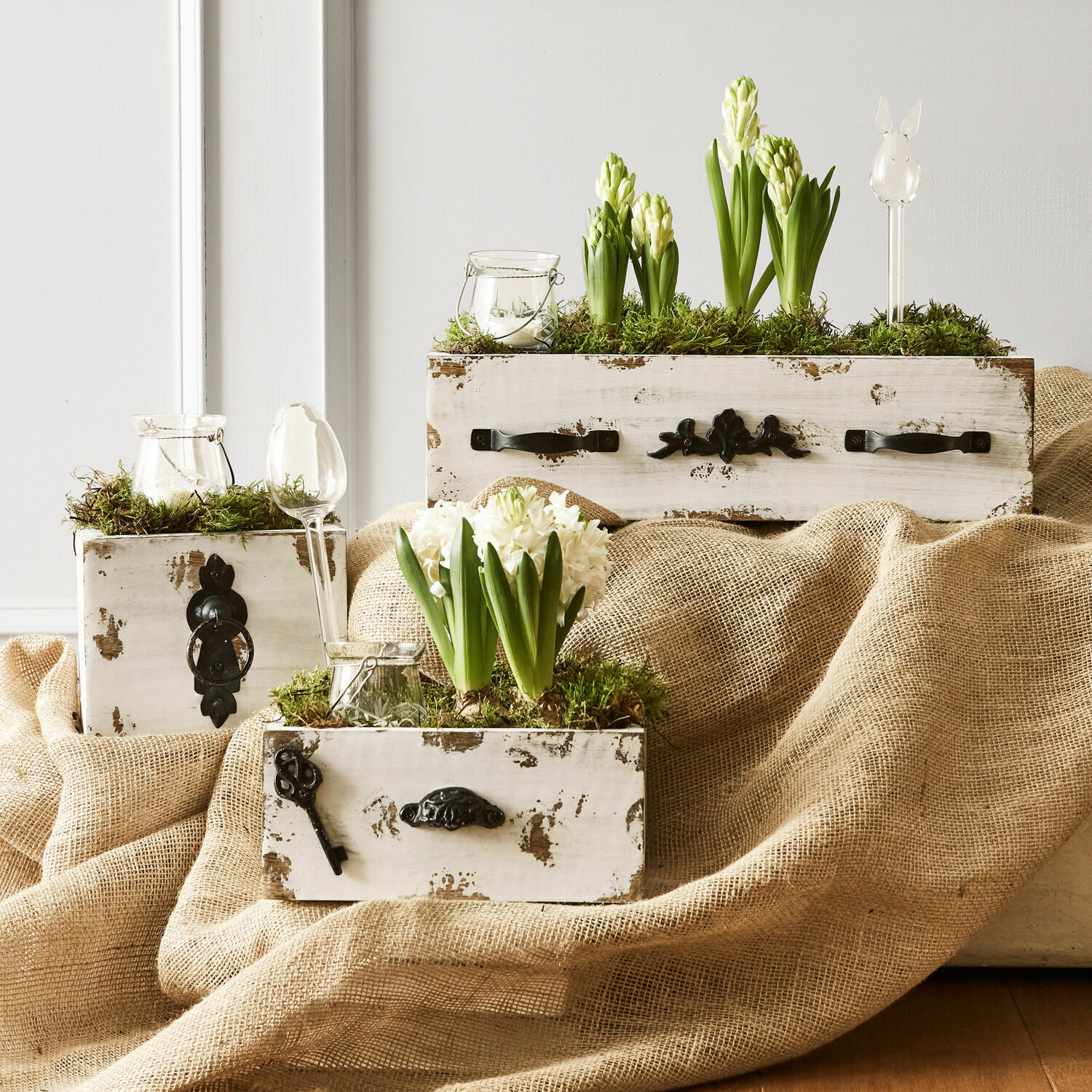 Lot de 3 caisses décoratives Gorik Coffrets en bois blanc vieilli avec des jacinthes blanches et vertes entourées de mousse décorative
