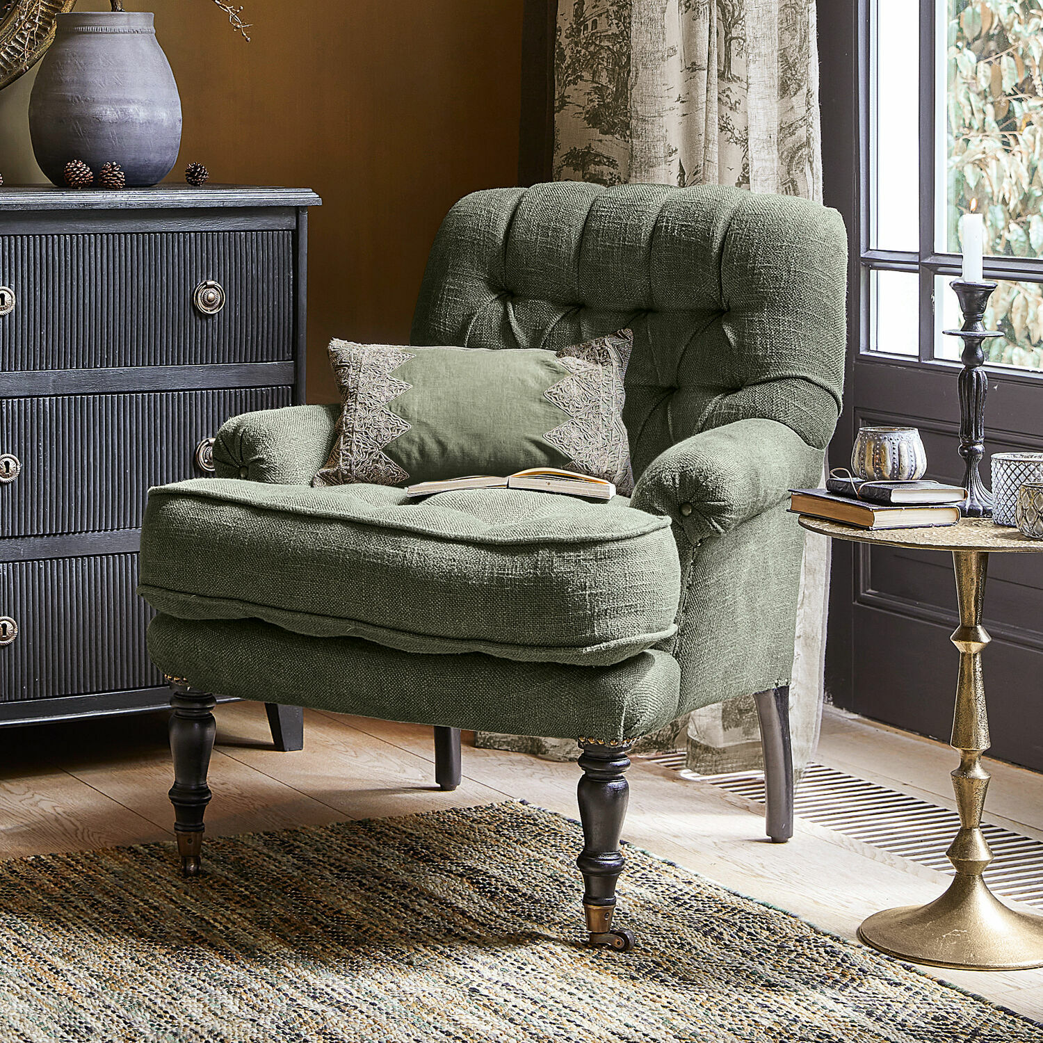 Fauteuil Gyldford Fauteuil vert en tissu avec coussin décoratif dans un salon chaleureux avec tapis tissé