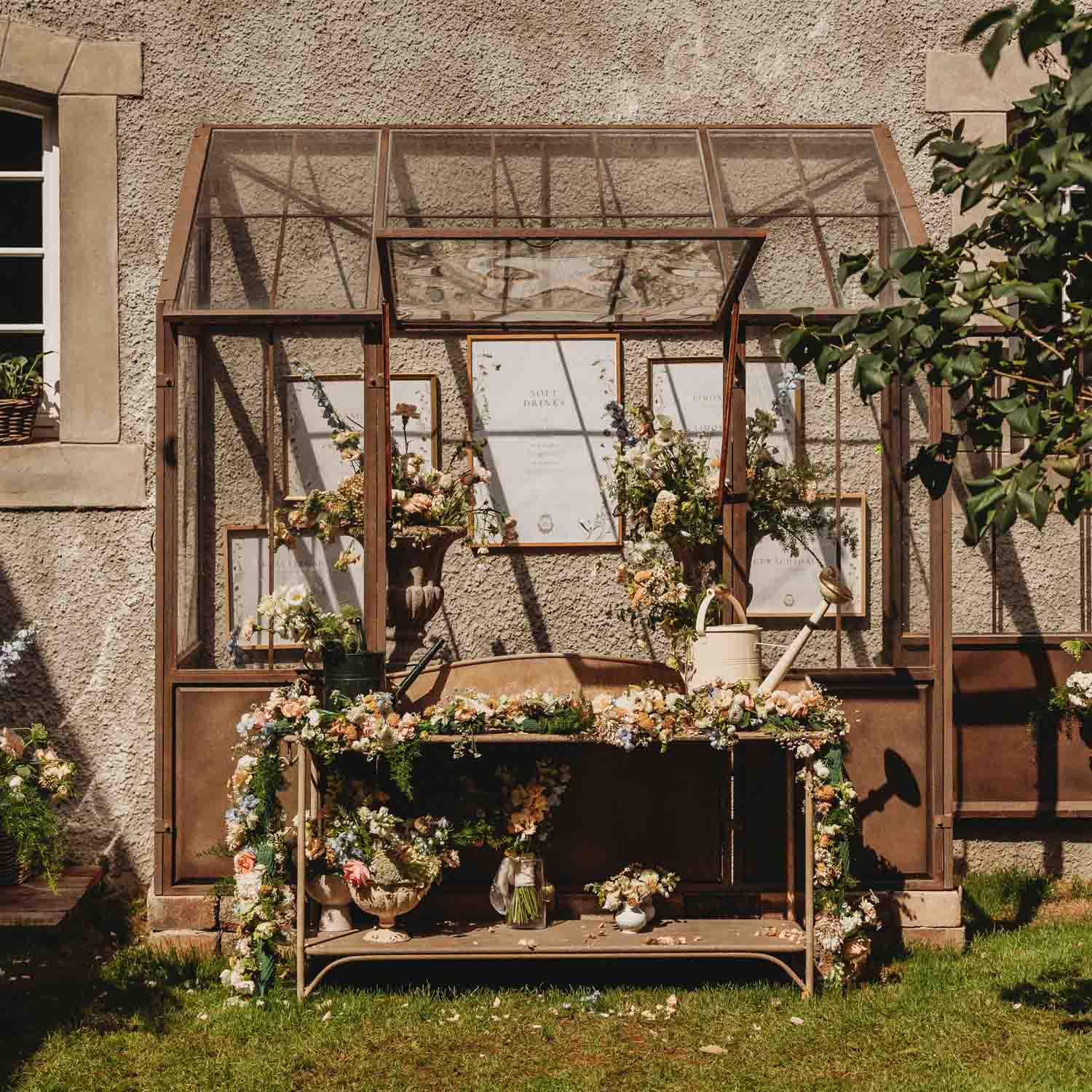 Banc de jardin en métal décoré de fleurs et arrosoir devant un mur texturé avec fenêtre