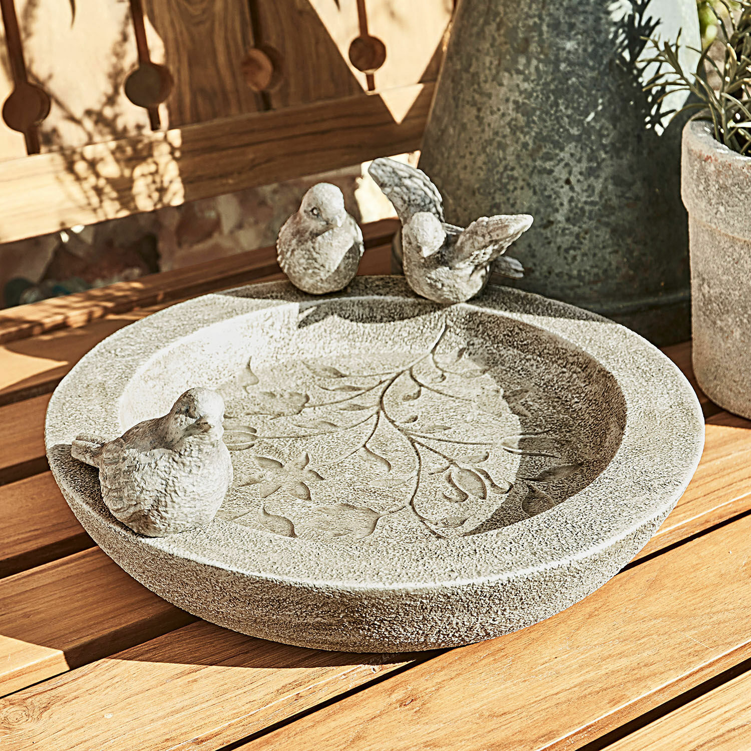 Abreuvoir à oiseaux Joalien Bain d'oiseaux décoratif en pierre grise avec motif de feuilles et trois oiseaux sur table en bois