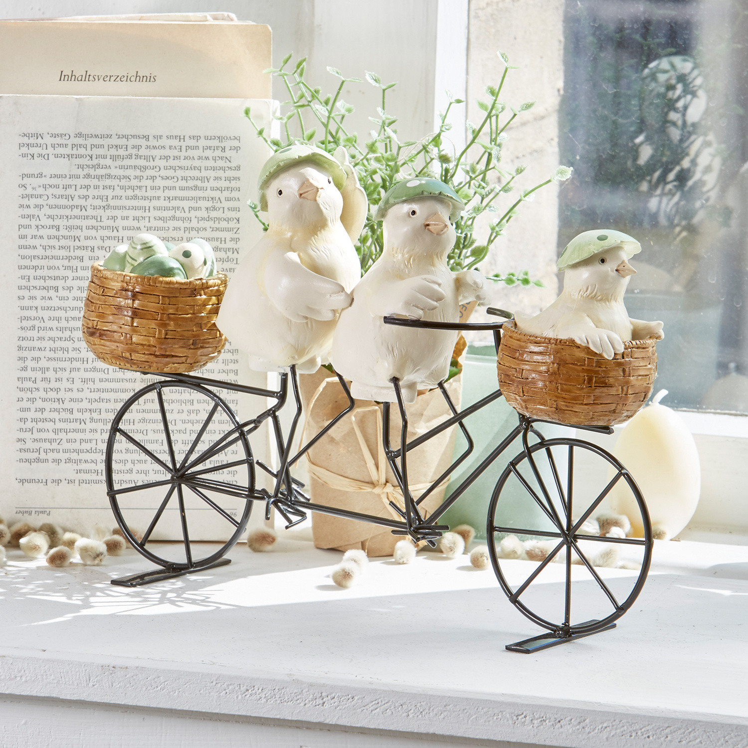 Poussins décoratifs Family Tour Décoration avec trois oiseaux blancs au chapeau vert sur un vélo en métal avec paniers en osier