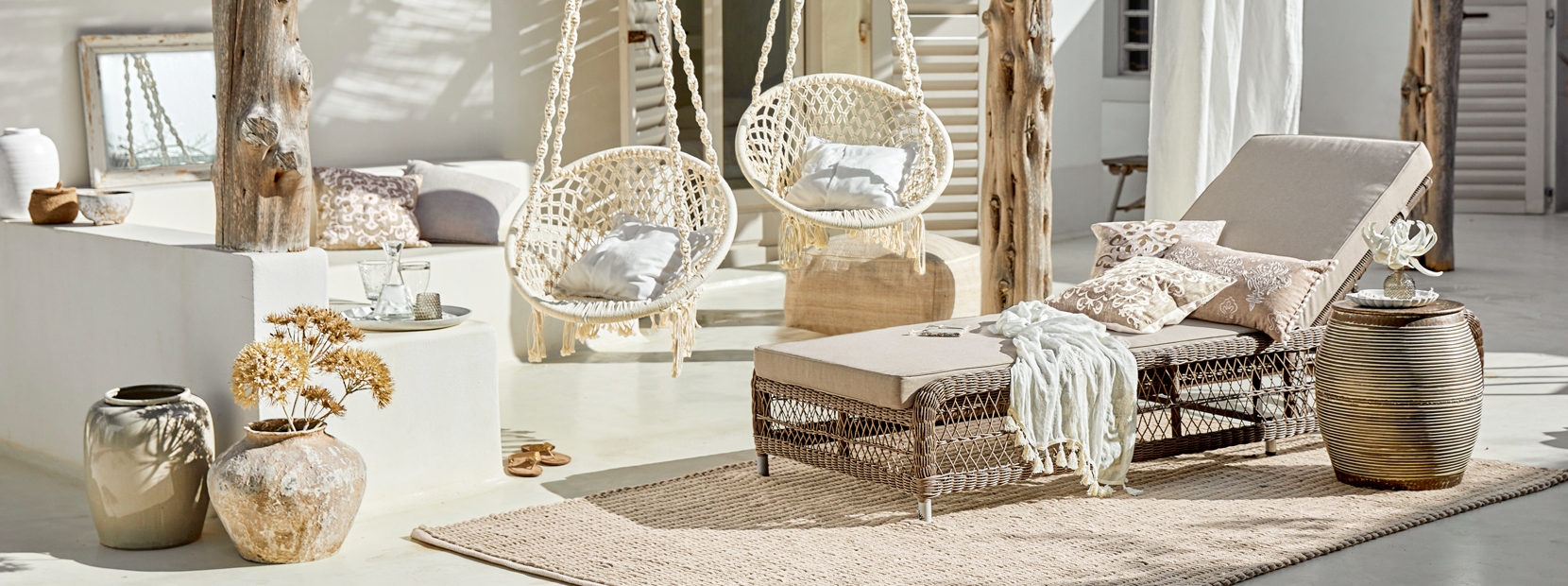 Salon bohème avec chaise longue en rotin et fauteuils suspendus en coton beige naturel