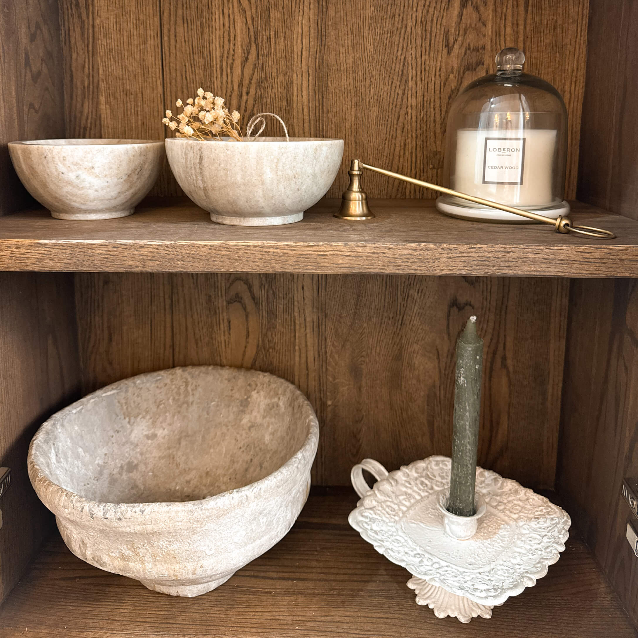 Bols en pierre décoratifs et bougeoir avec bougie verte sur étagère en bois style rustique