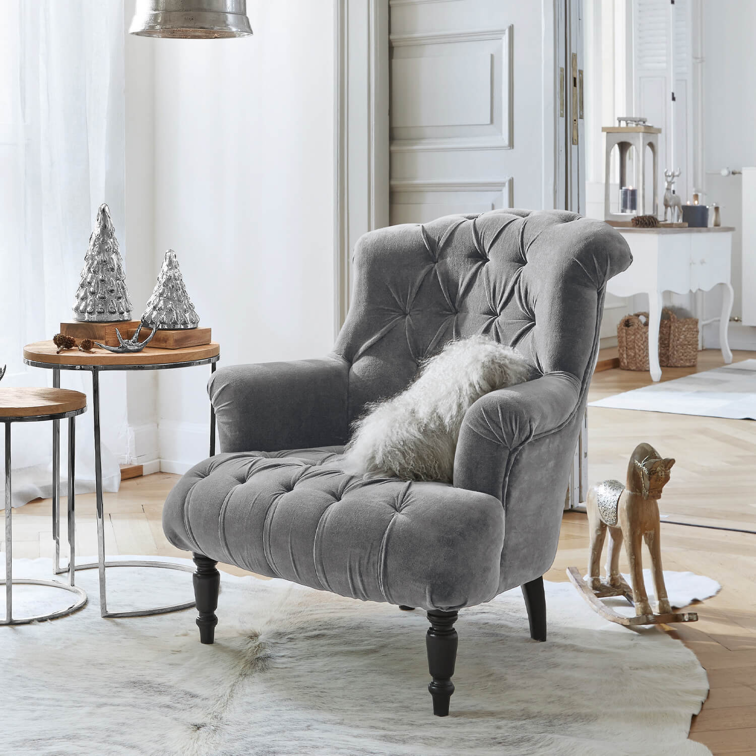 Fauteuil gris en velours avec dossier capitonné et pieds noirs dans un salon lumineux décoré pour Noël