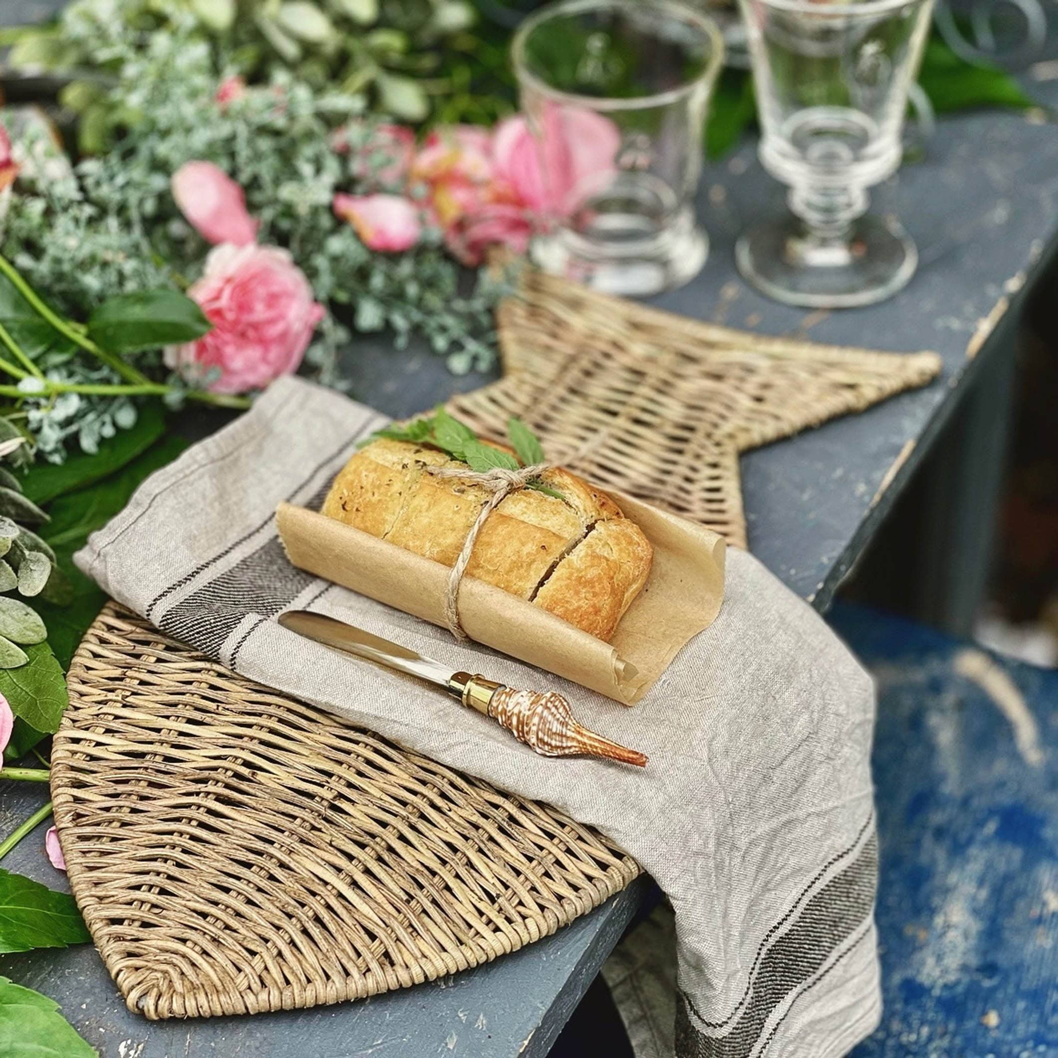 Set de table en herbe marine tressée avec pain et couteau à manche coquillage sur table rustique