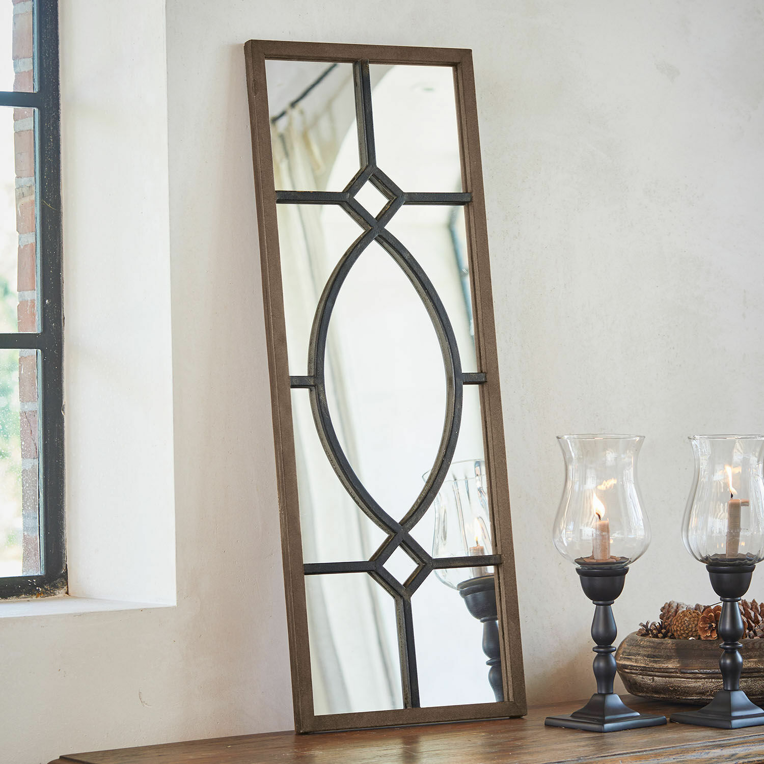 Miroir Millery Miroir rectangulaire avec cadre en bois brun et motif métallique noir posé sur une table avec des lanternes