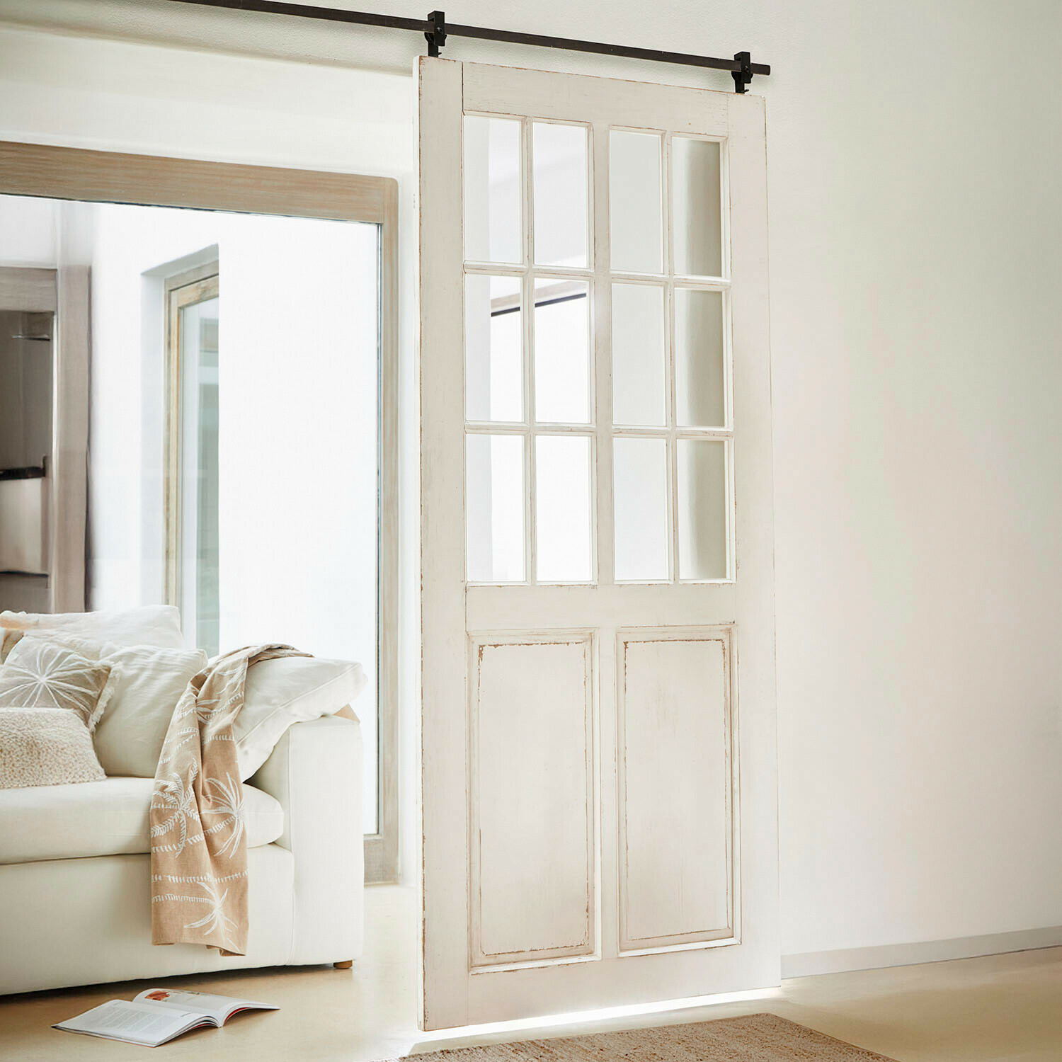 Porte coulissante Sorelles Porte coulissante en bois blanc avec panneaux vitrés dans un salon lumineux et moderne