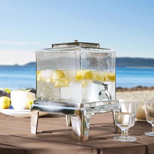 Distributeur de boissons en verre avec support métallique, rempli d'eau citronnée, parfait pour les réceptions d'été