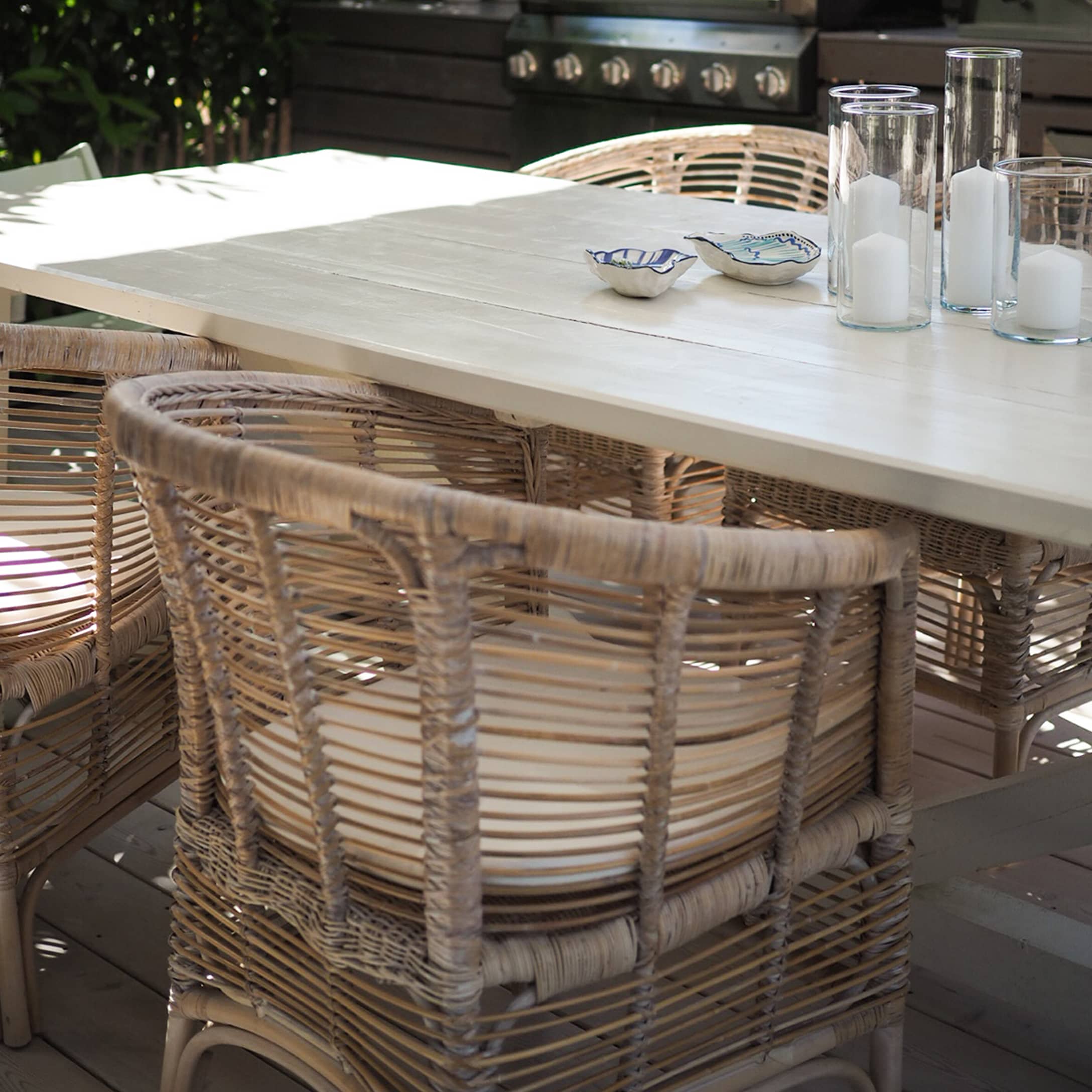 Ensemble de meubles de jardin en rotin clair avec table en bois blanc sur terrasse ensoleillée