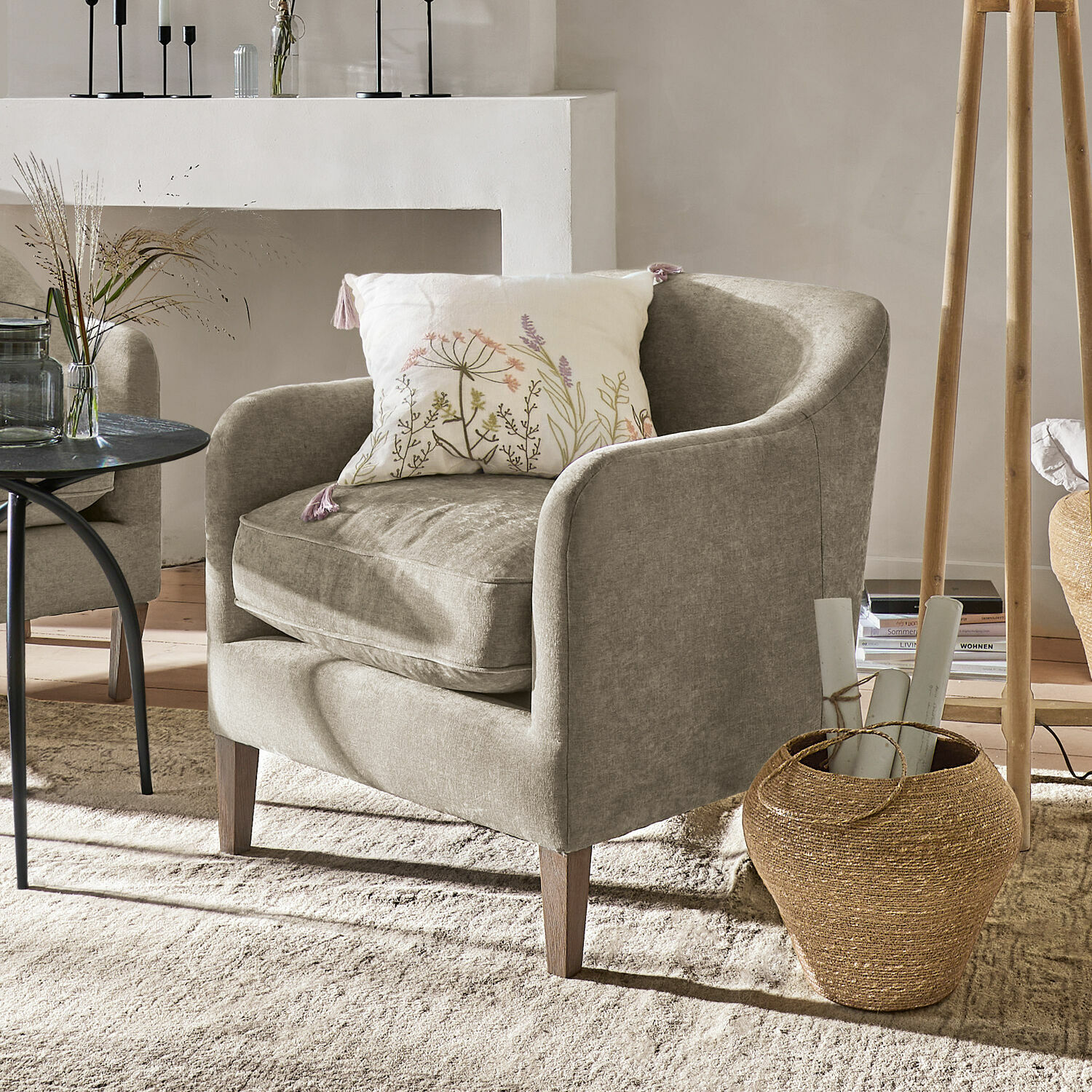Fauteuil Jefferson Fauteuil beige en tissu avec coussin floral dans un salon lumineux et chaleureux