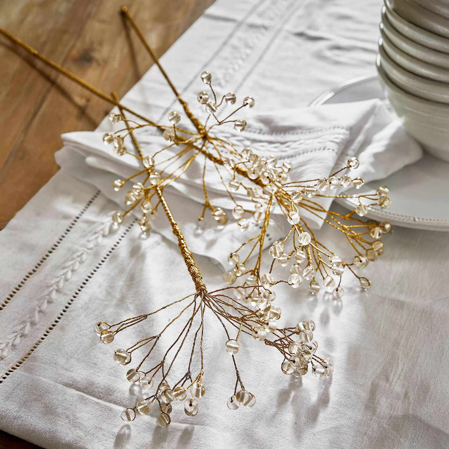 Lot de 3 décorations à piquer Nimweth Branches décoratives dorées avec perles transparentes posées sur une nappe blanche, décoration de table