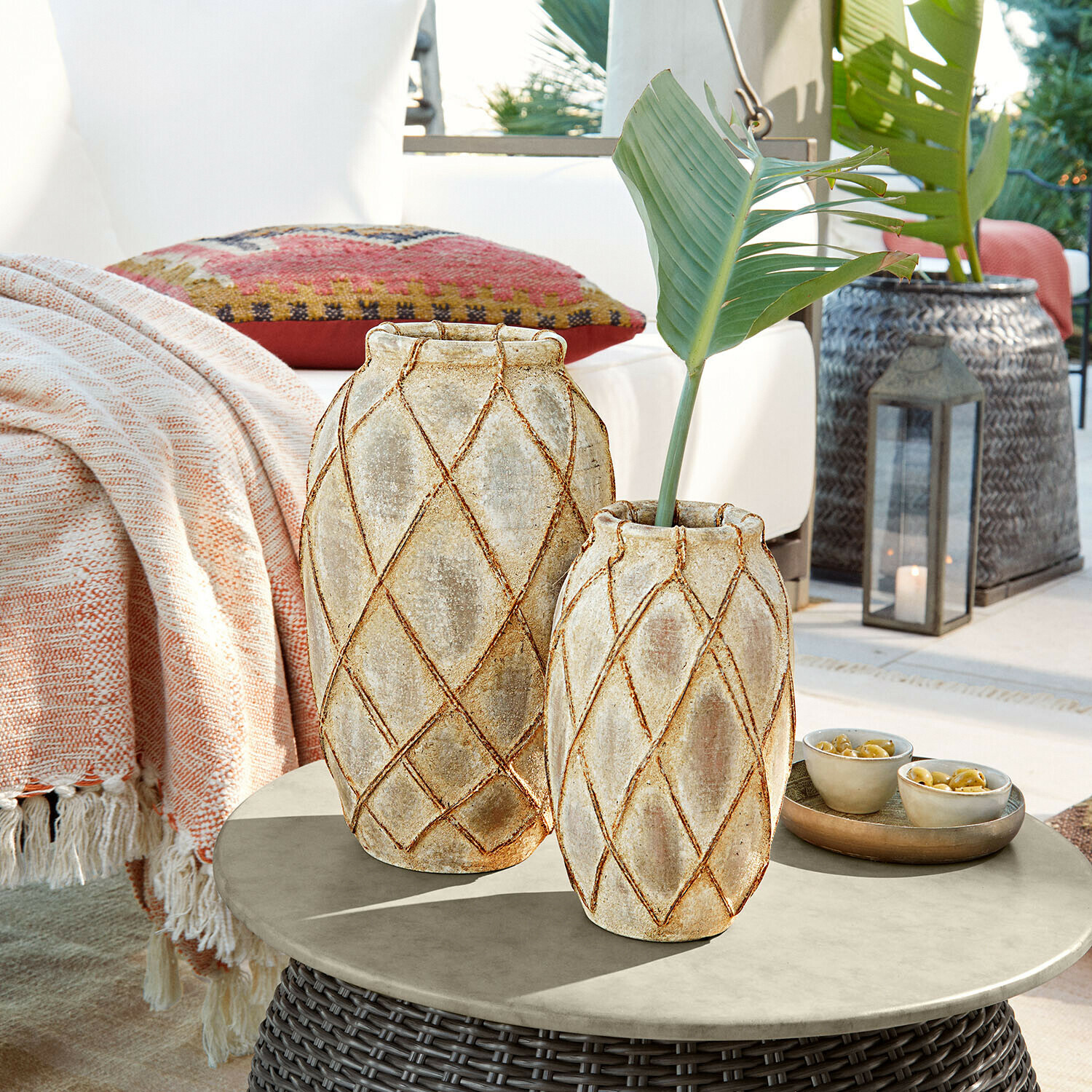 Lot de 2 vases Deloriva Deux vases en céramique beige avec motif géométrique posés sur une table d'extérieur en rotin