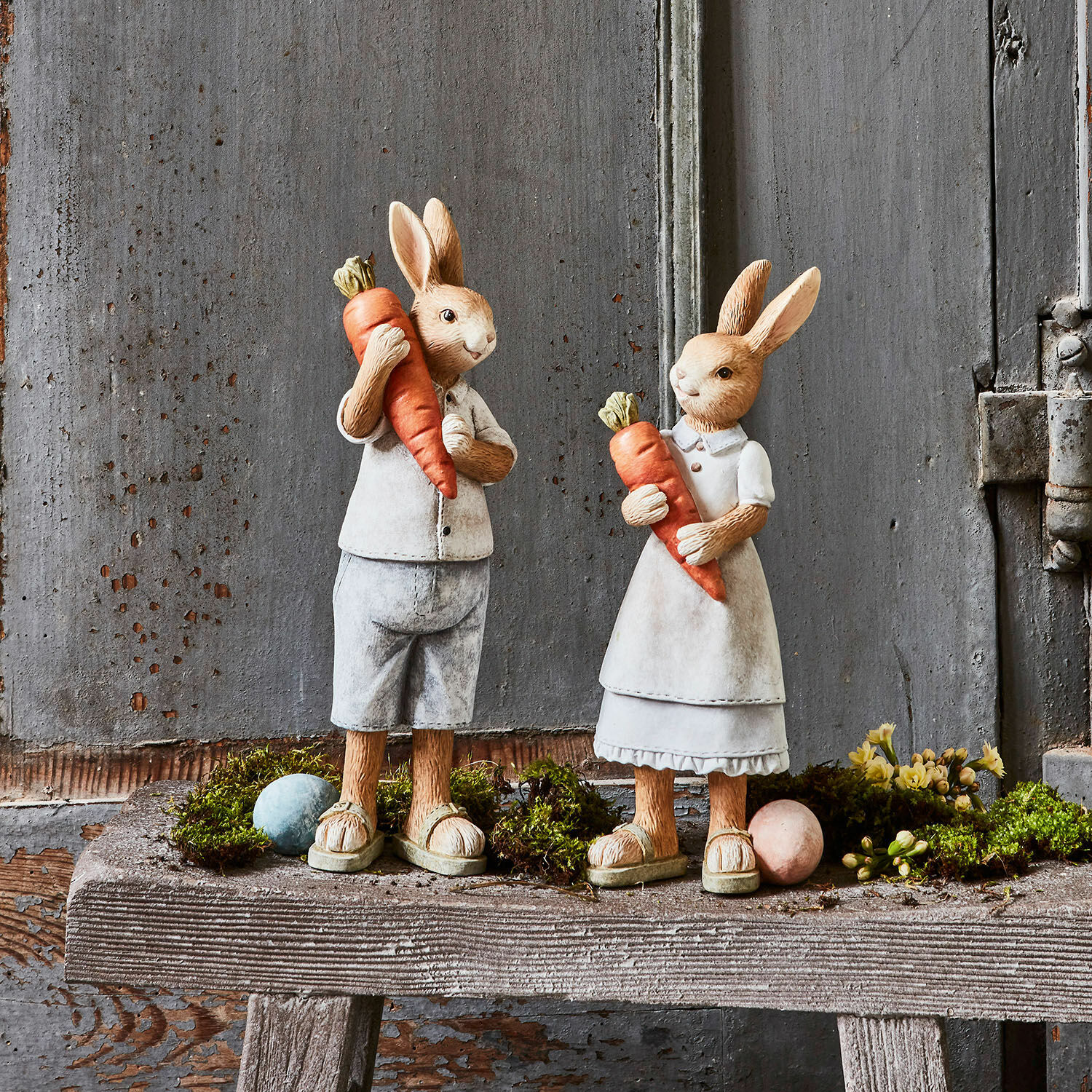 Lot de 2 lapins Gimont Figurines de lapins en matériau beige tenant des carottes orange sur un banc en bois rustique