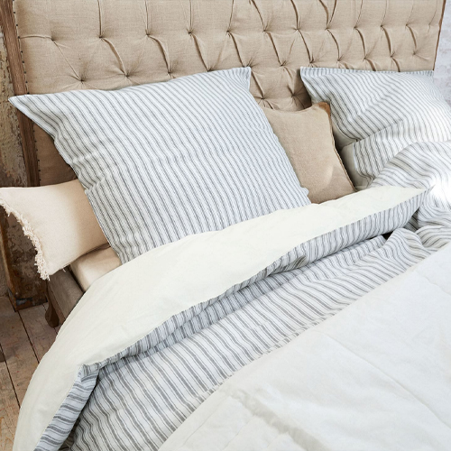 Parure de lit en coton rayé gris sur tête de lit capitonnée beige, élégante et confortable