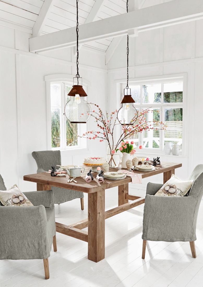 Salle à manger avec table en bois massif et chaises grises dans un intérieur blanc lumineux