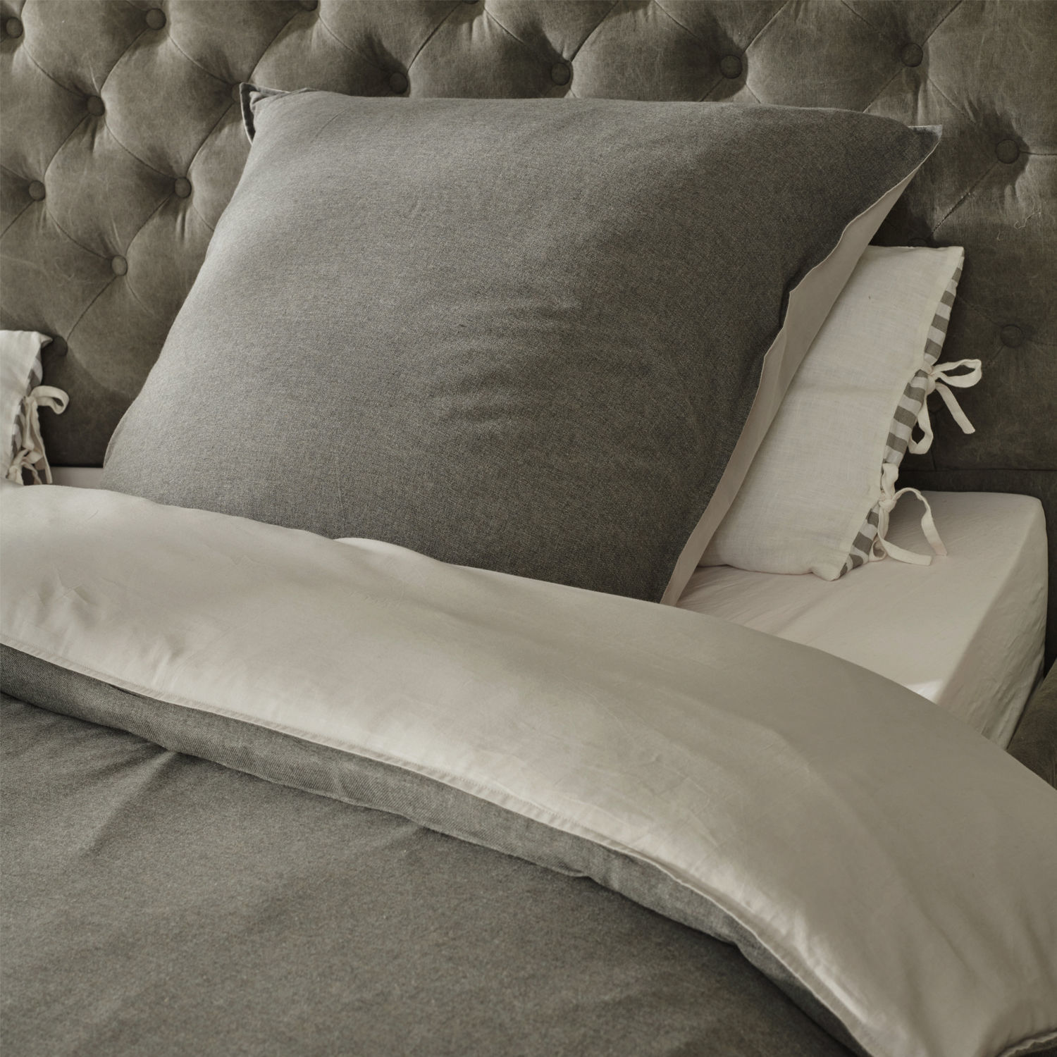 Parure de lit Mynatt Parure de lit grise en tissu doux sur un lit avec tête de lit capitonnée, confortable et élégante