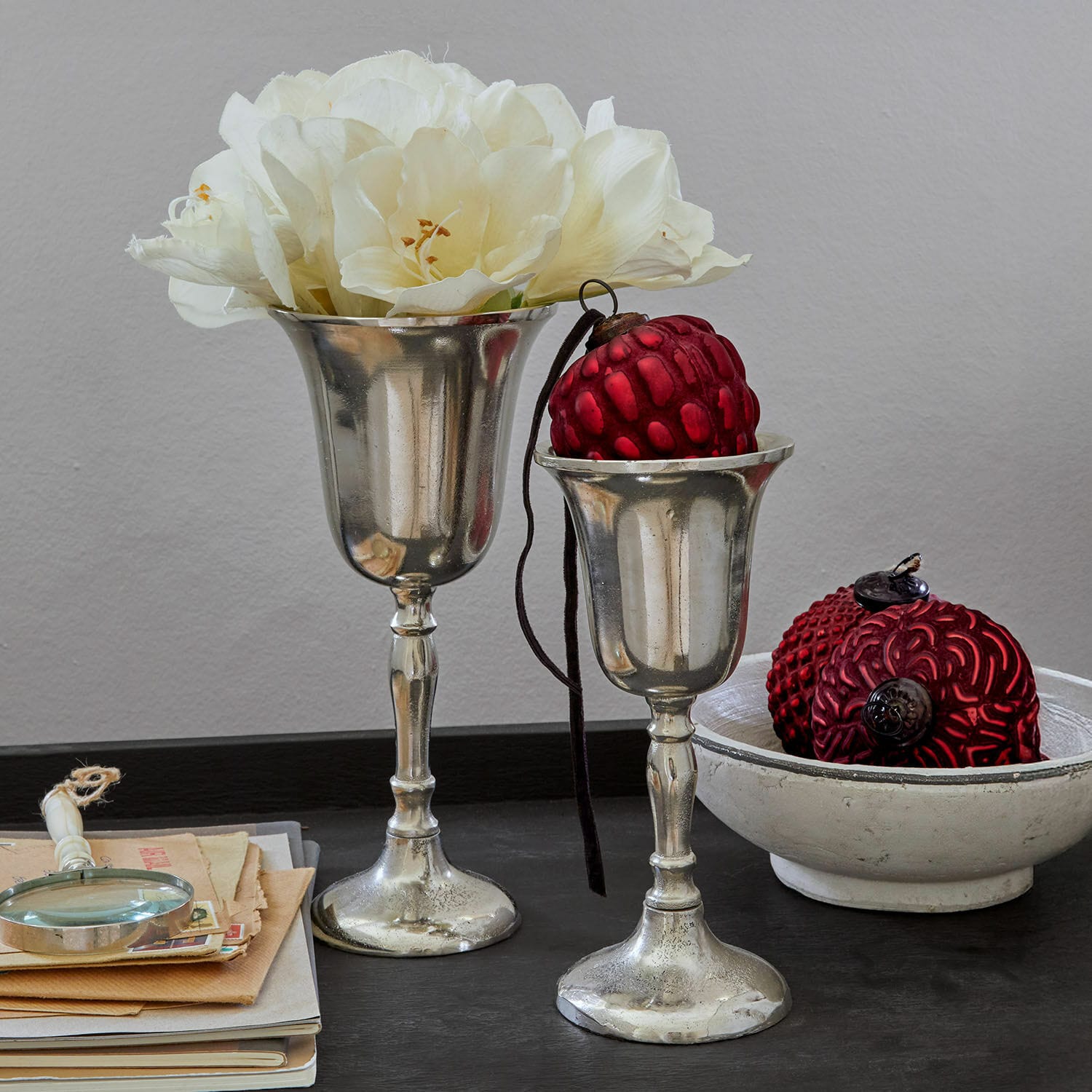 Lot de 2 vases Solérie Deux coupes argentées décoratives avec fleurs blanches et ornements rouges sur table noire