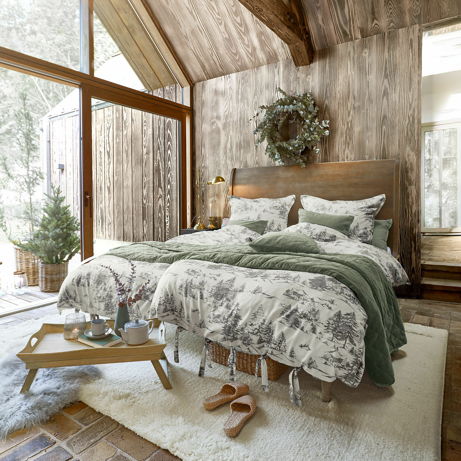 Parure de lit Héroux Chambre chaleureuse avec mur en bois et lit avec linge de lit vert et motifs forêt gris