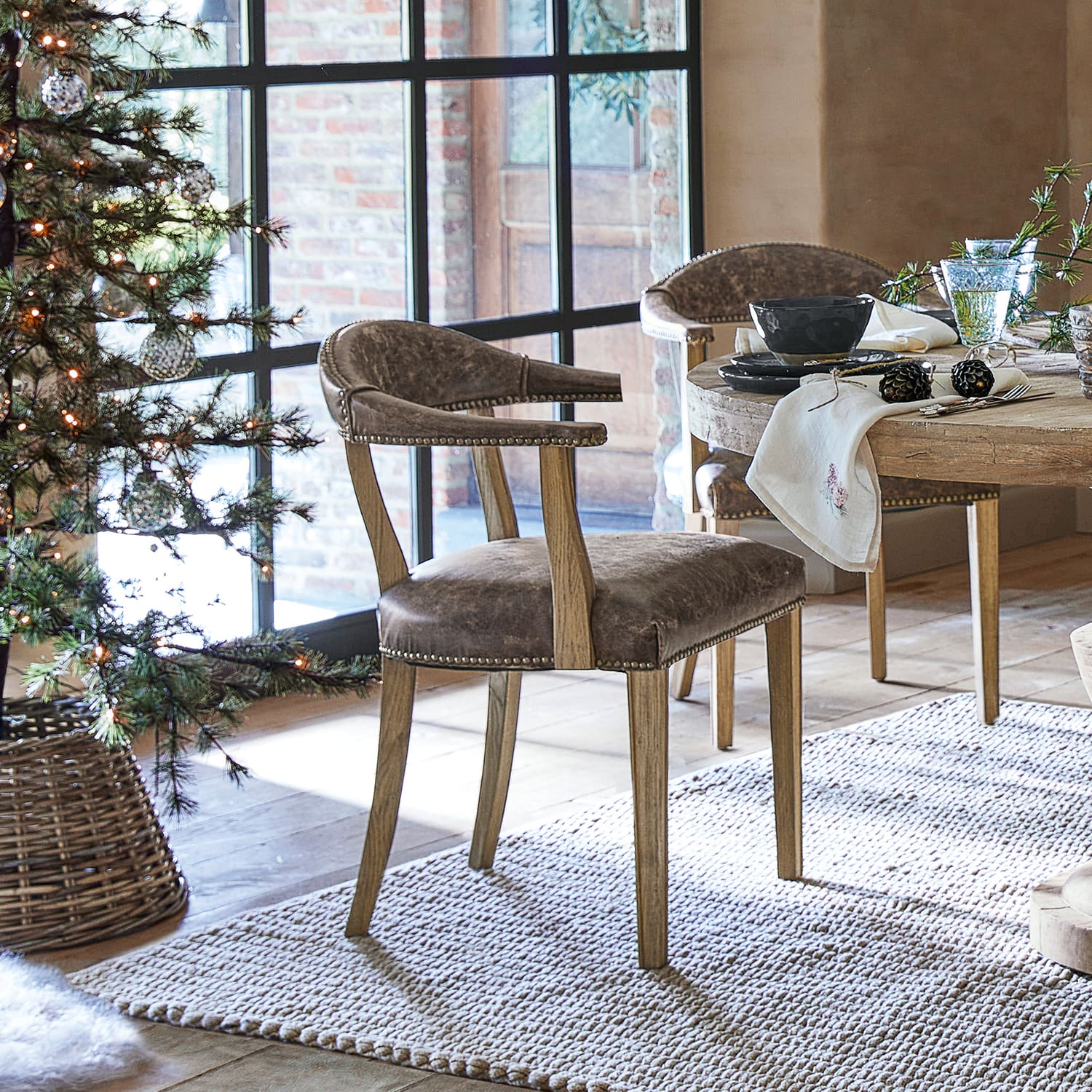 Chaise de salle à manger en cuir marron et bois de chêne dans un style rustique près d'une table en bois