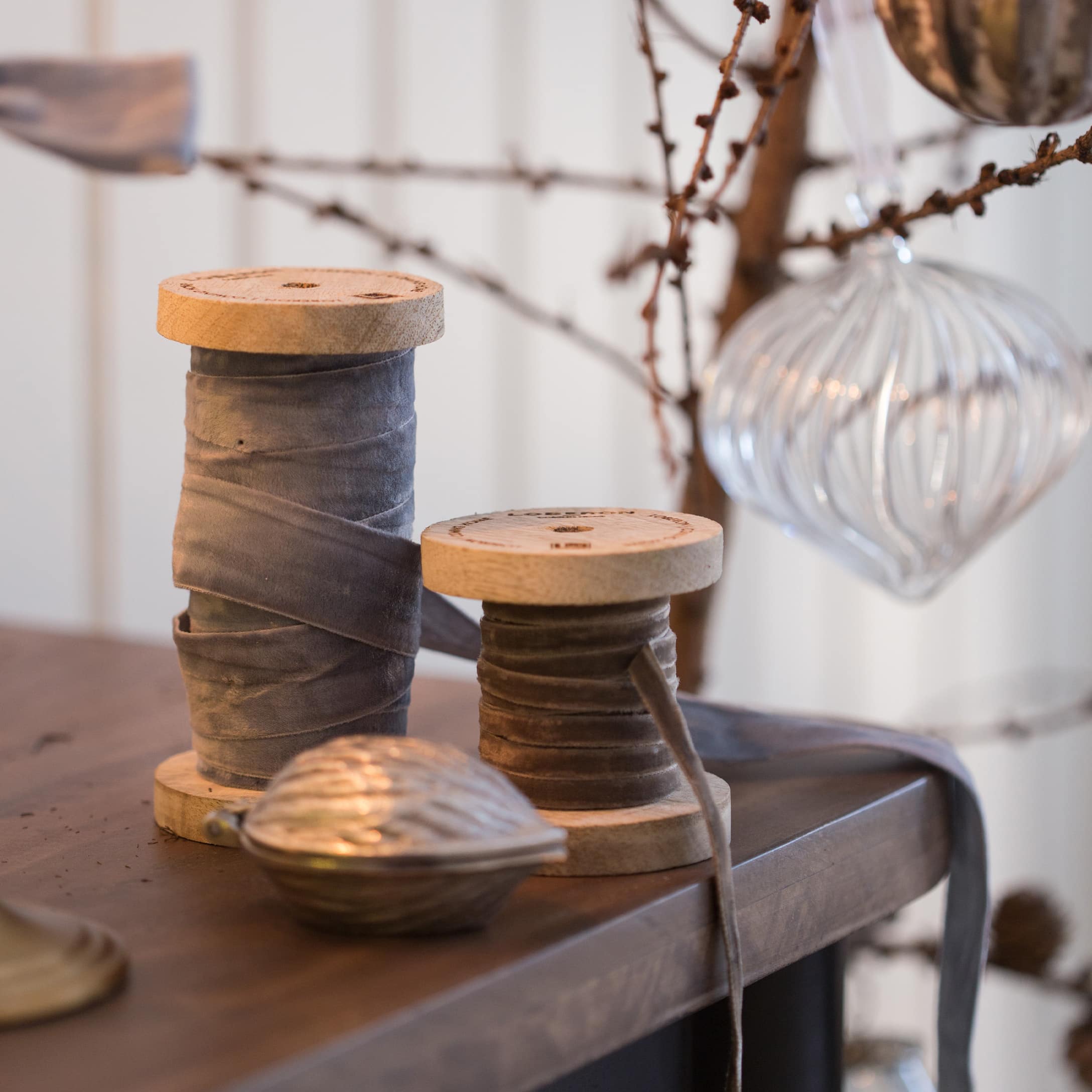 Bobines en bois avec ruban en velours gris sur une table en bois avec décoration de Noël