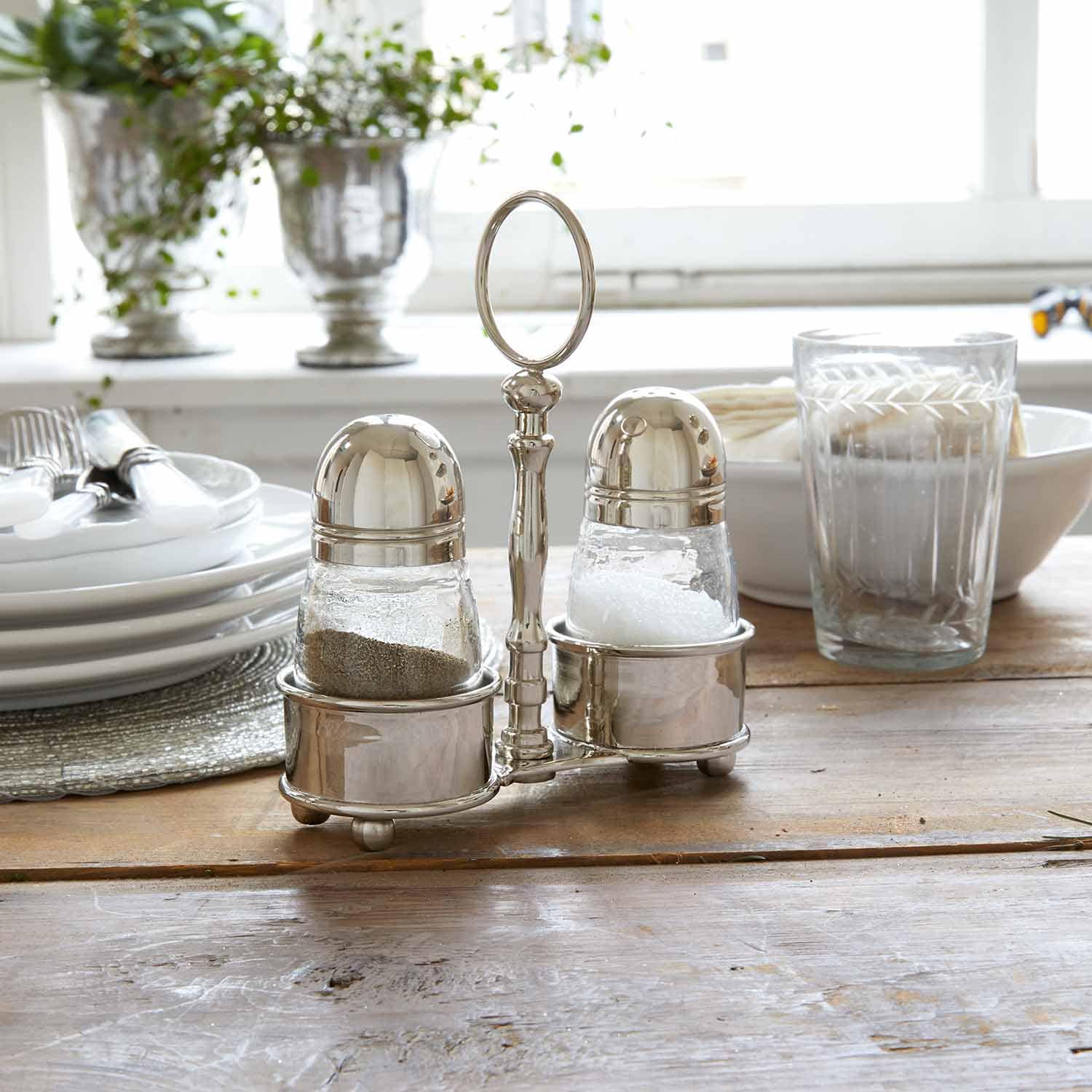 Ensemble salière et poivrière en acier inoxydable sur table en bois dans une cuisine lumineuse