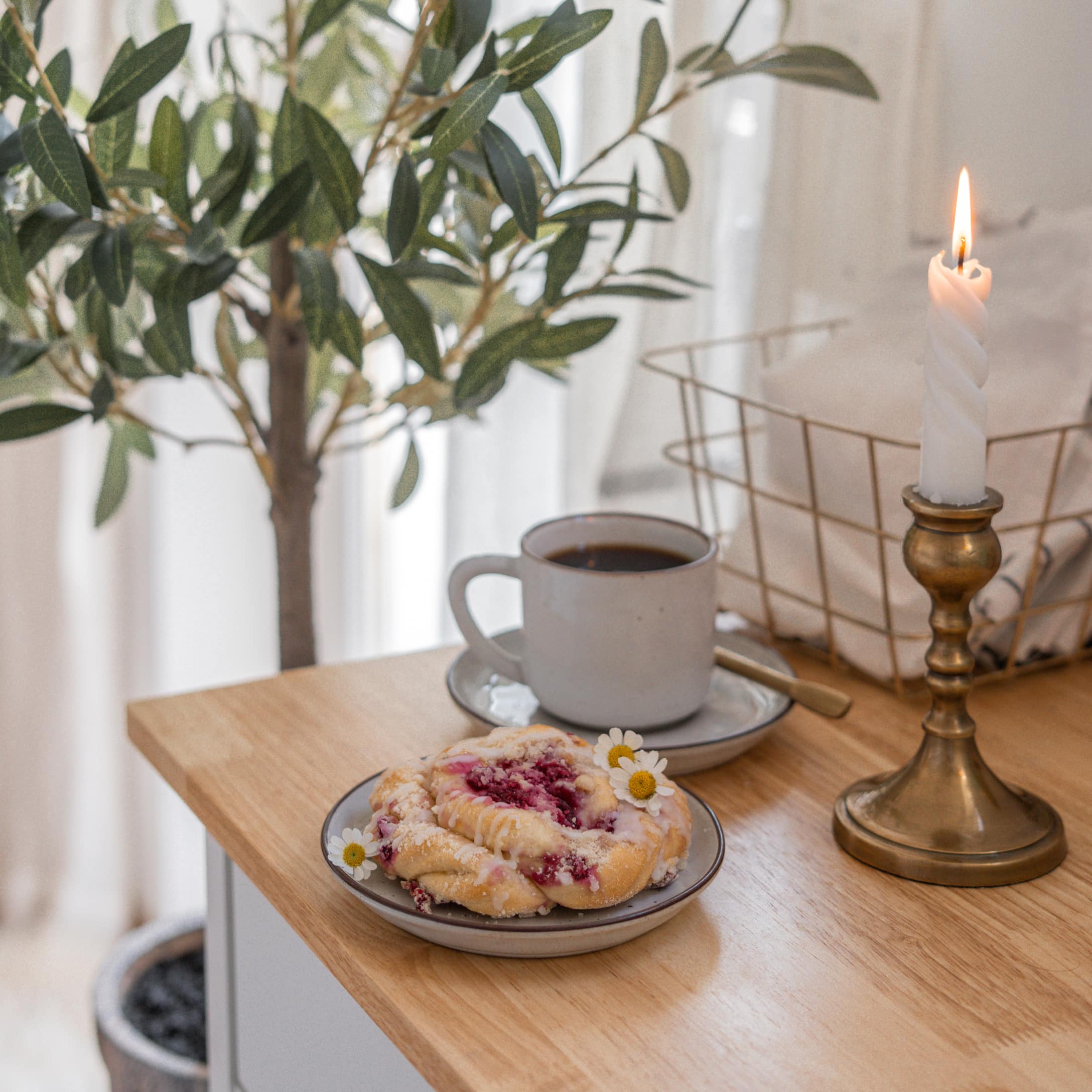 Bougeoir torsadé en laiton doré sur table en bois avec tasse de café et pâtisserie aux fruits rouges