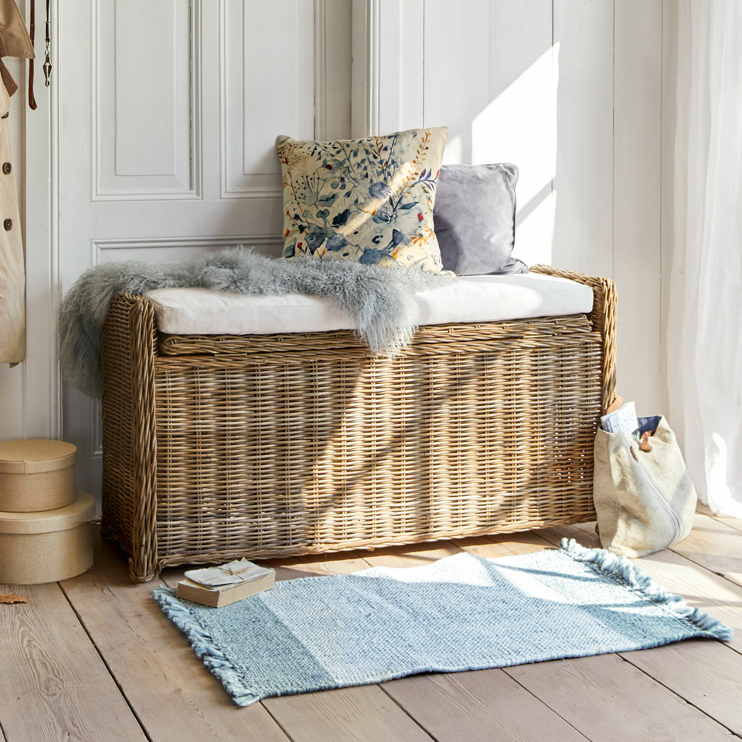 Banc Horton Banc en rotin naturel avec coussin blanc et coussins décoratifs dans une pièce lumineuse