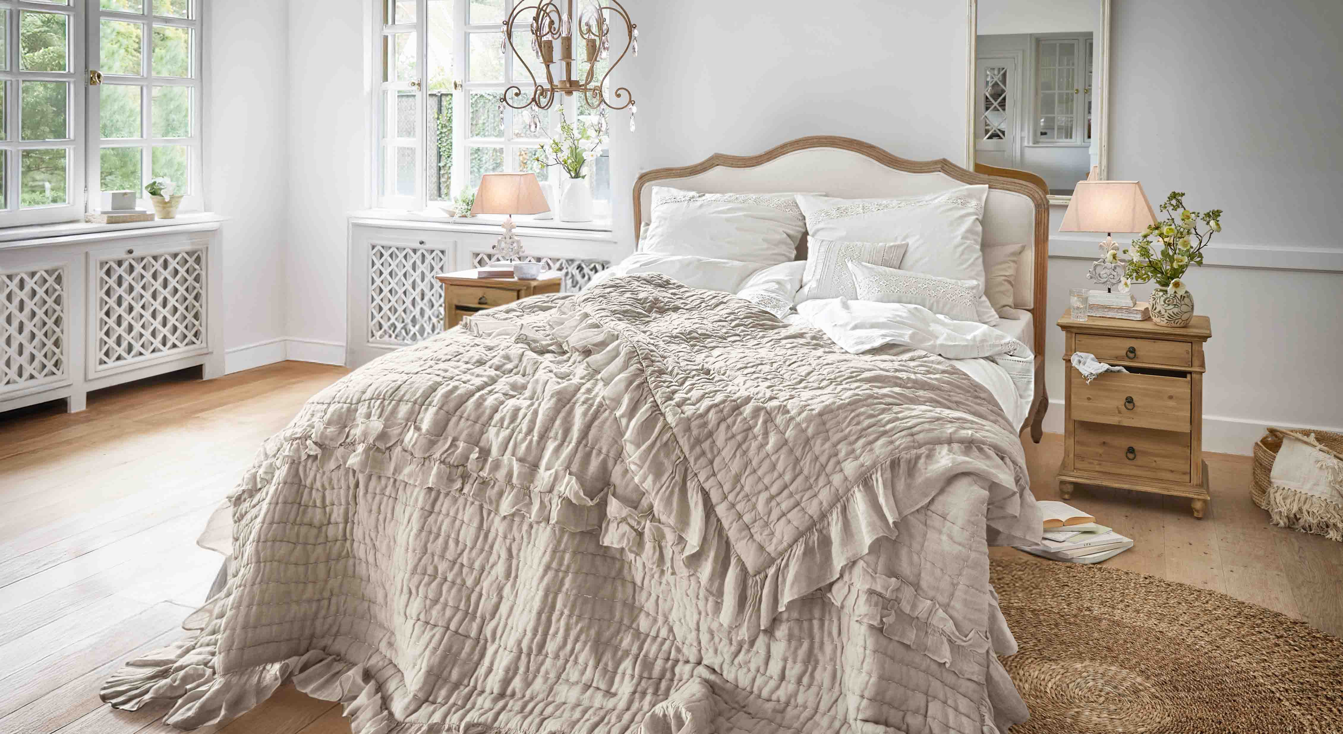 Chambre chaleureuse avec lit en couvre-lit beige à volants et tables de chevet en bois clair