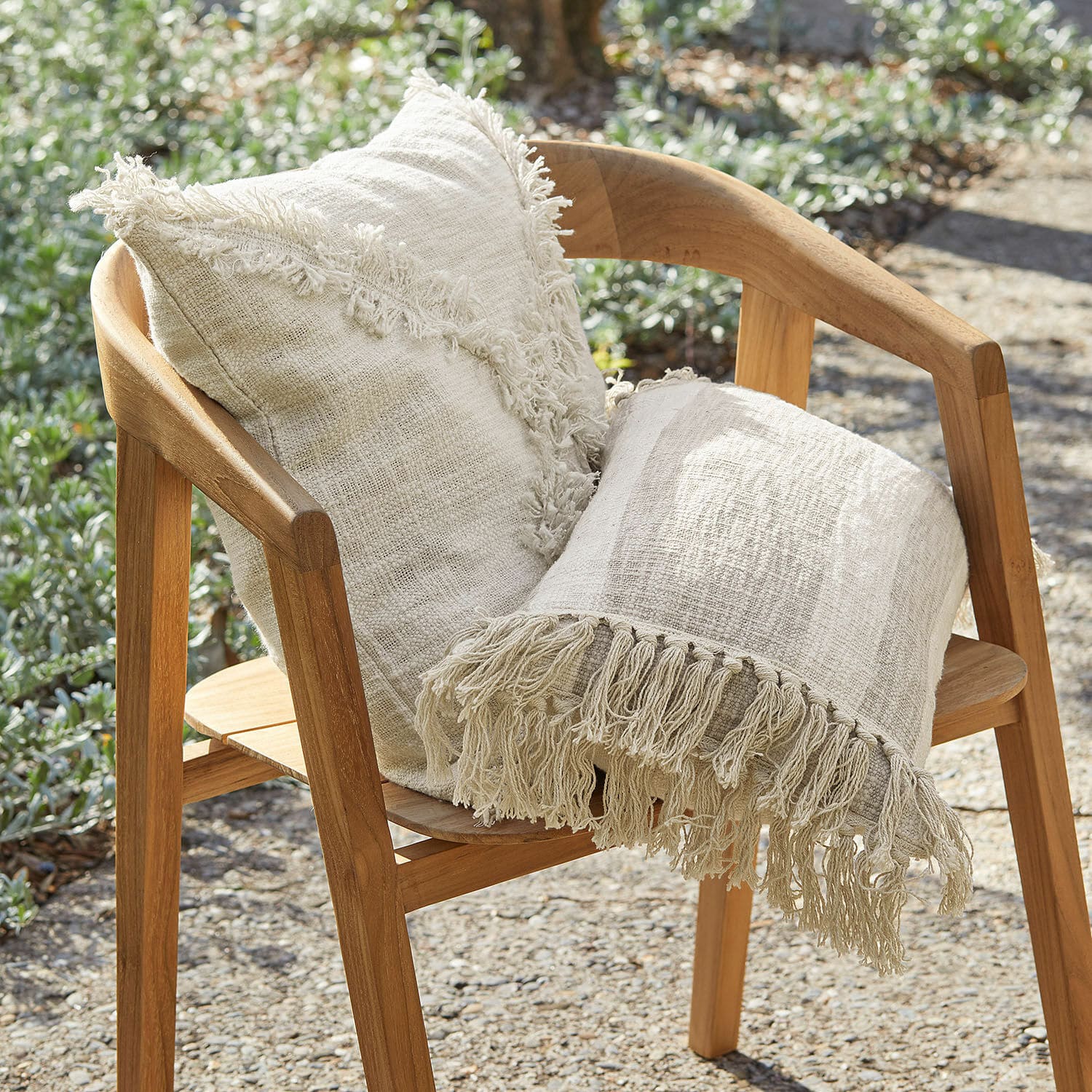Lot de 2 housses de coussins Freya Coussin beige en coton et plaid à franges sur chaise en bois pour jardin extérieur
