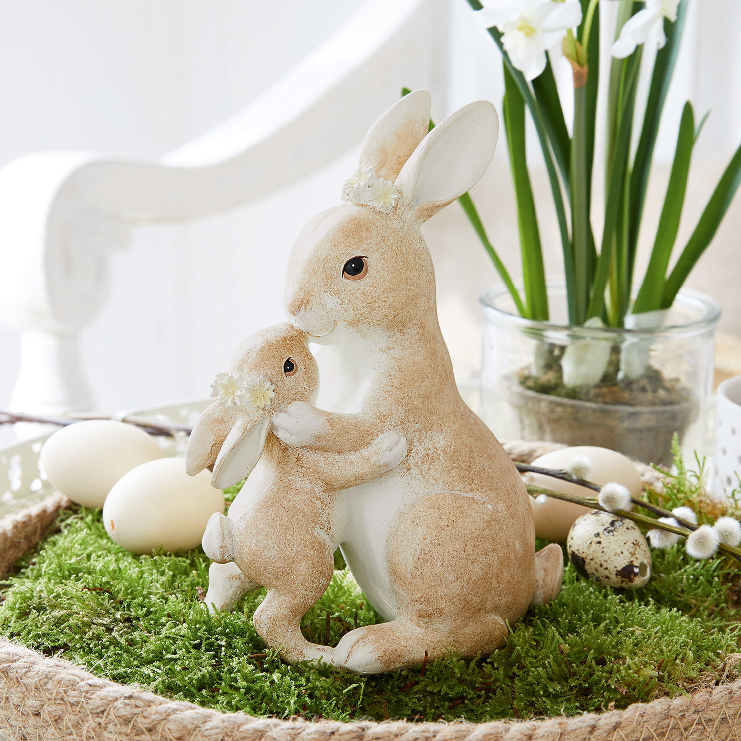 Lapins Aliena Figurines de deux lapins beige et blanc avec décorations florales sur mousse verte, décoration de Pâques