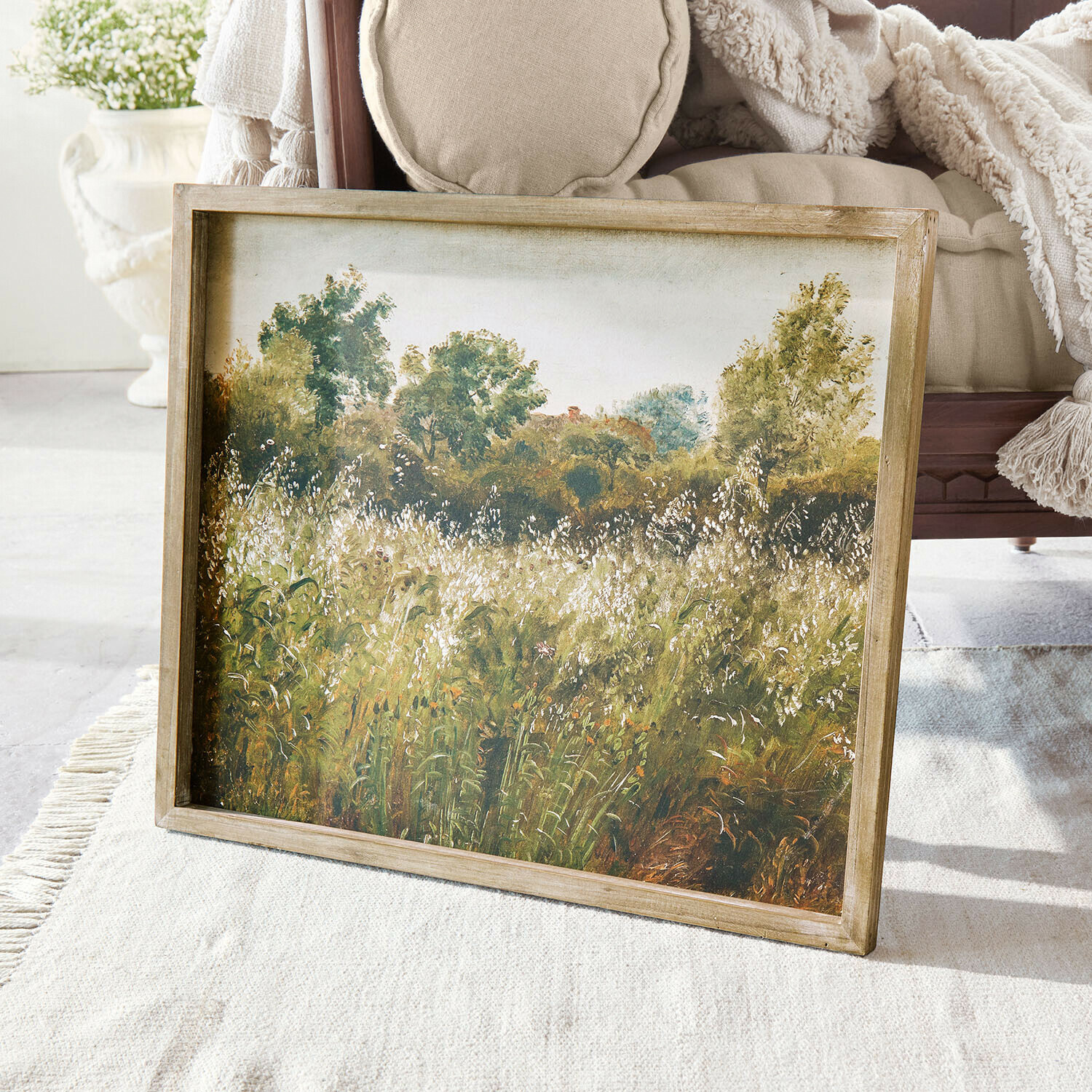 Tableau Vallerine Tableau paysage avec arbres verts et prairie encadré en bois posé sur un tapis clair