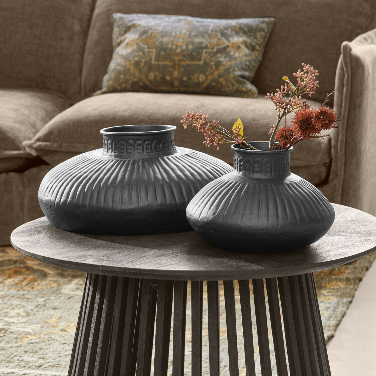 Lot de 2 vases Myrkja Deux vases en céramique noire avec motif rainuré sur une table en bois dans un salon