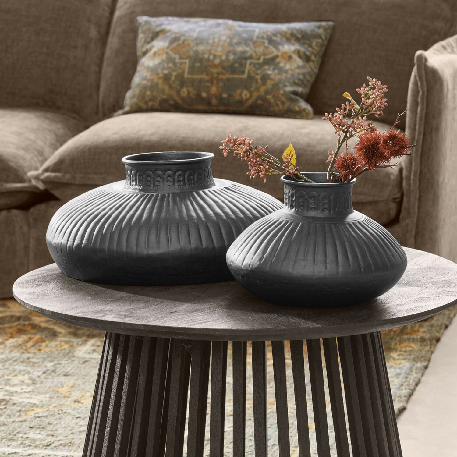 Lot de 2 vases Myrkja Deux vases en céramique noire avec motif rainuré sur une table en bois dans un salon