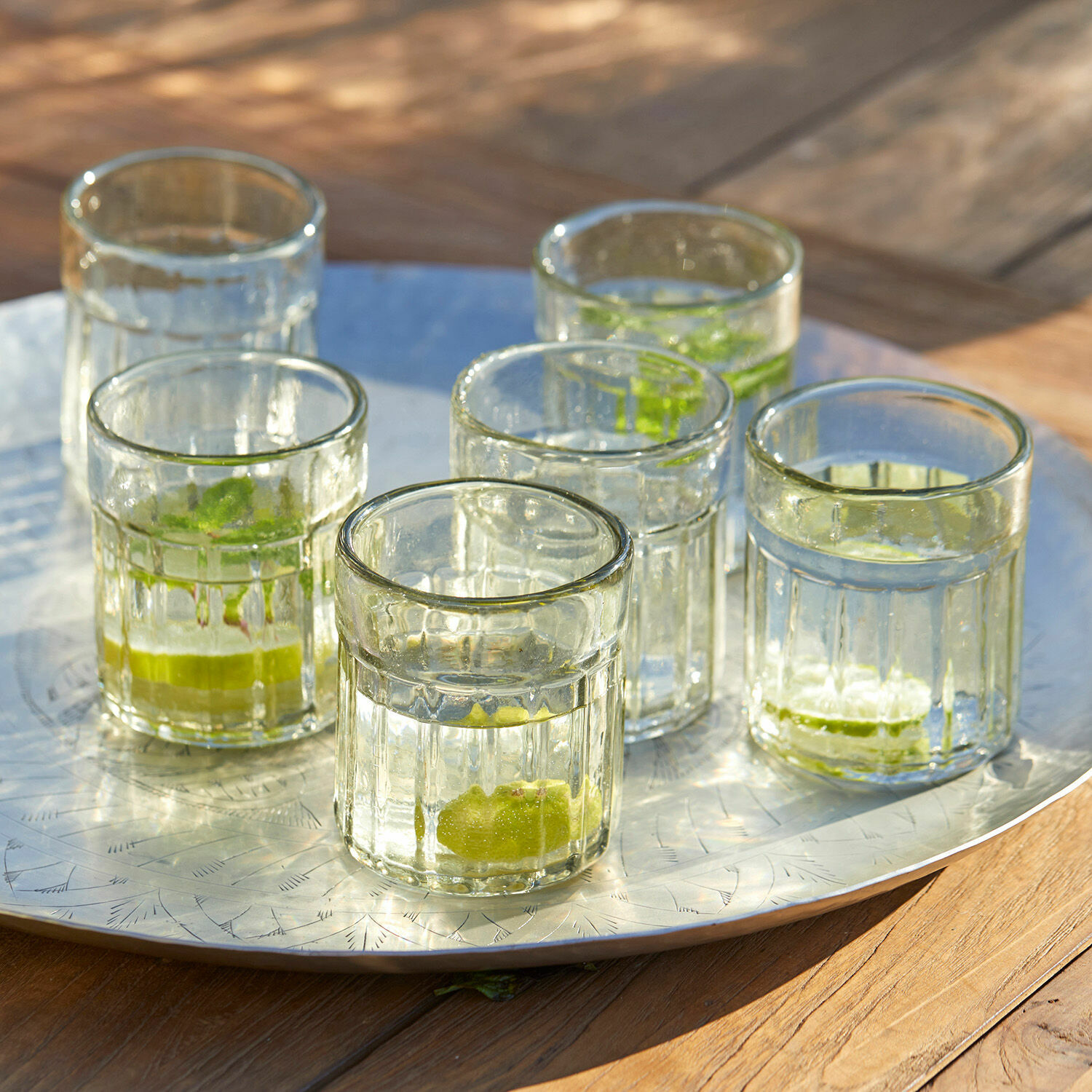 Lot de 6 verres Roseville Six verres en verre transparent avec citron vert sur un plateau en métal sur une table en bois