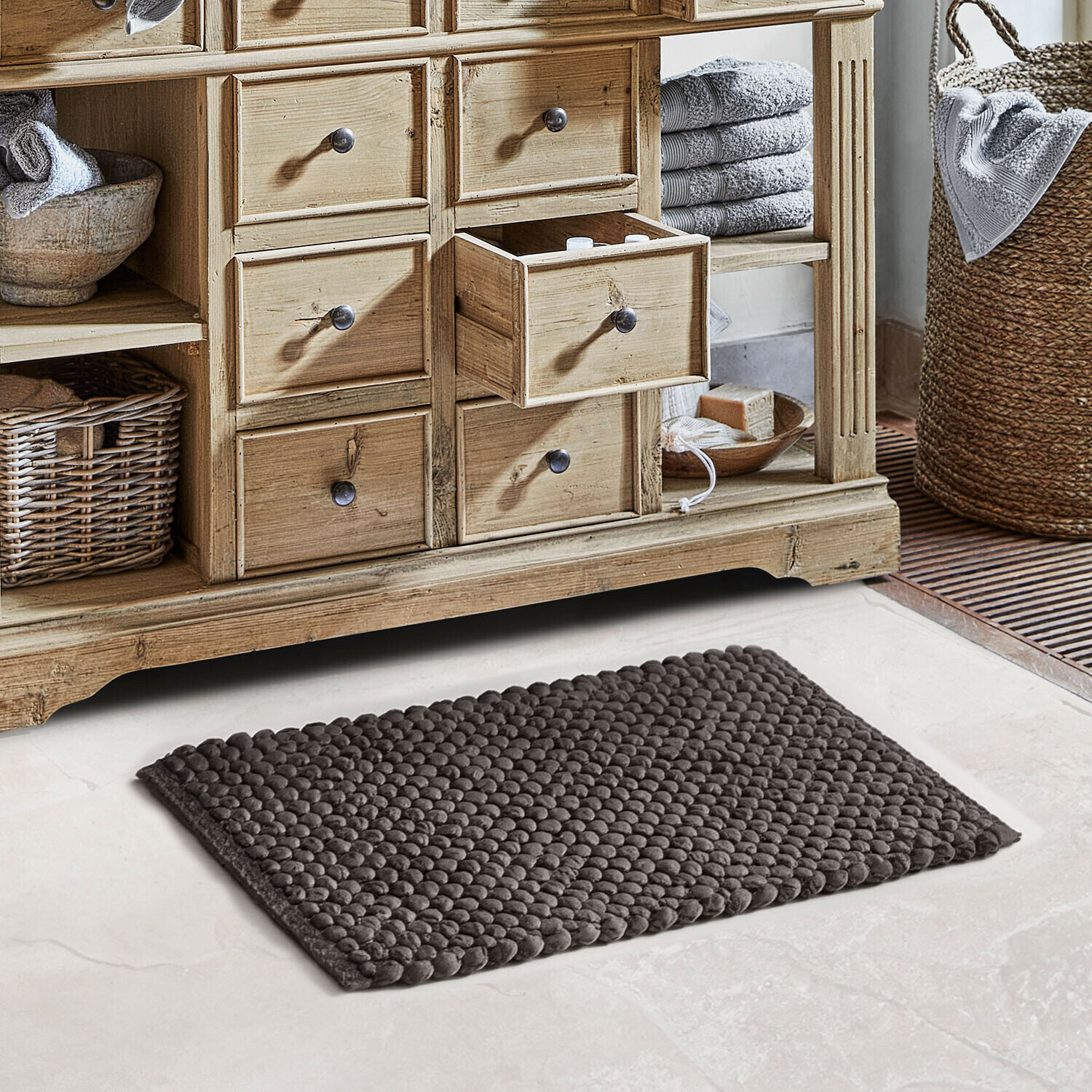 Tapis de bain Coldwyn Commode en bois naturel avec tiroirs, serviettes grises et tapis de bain texturé dans la salle de bain