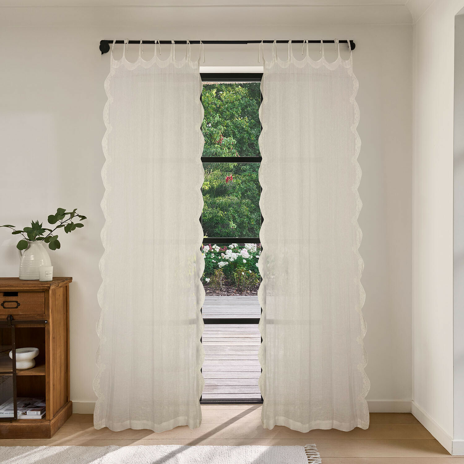 Voilage Dolcin Rideaux blancs transparents à bord ondulé dans une pièce lumineuse avec vue sur jardin
