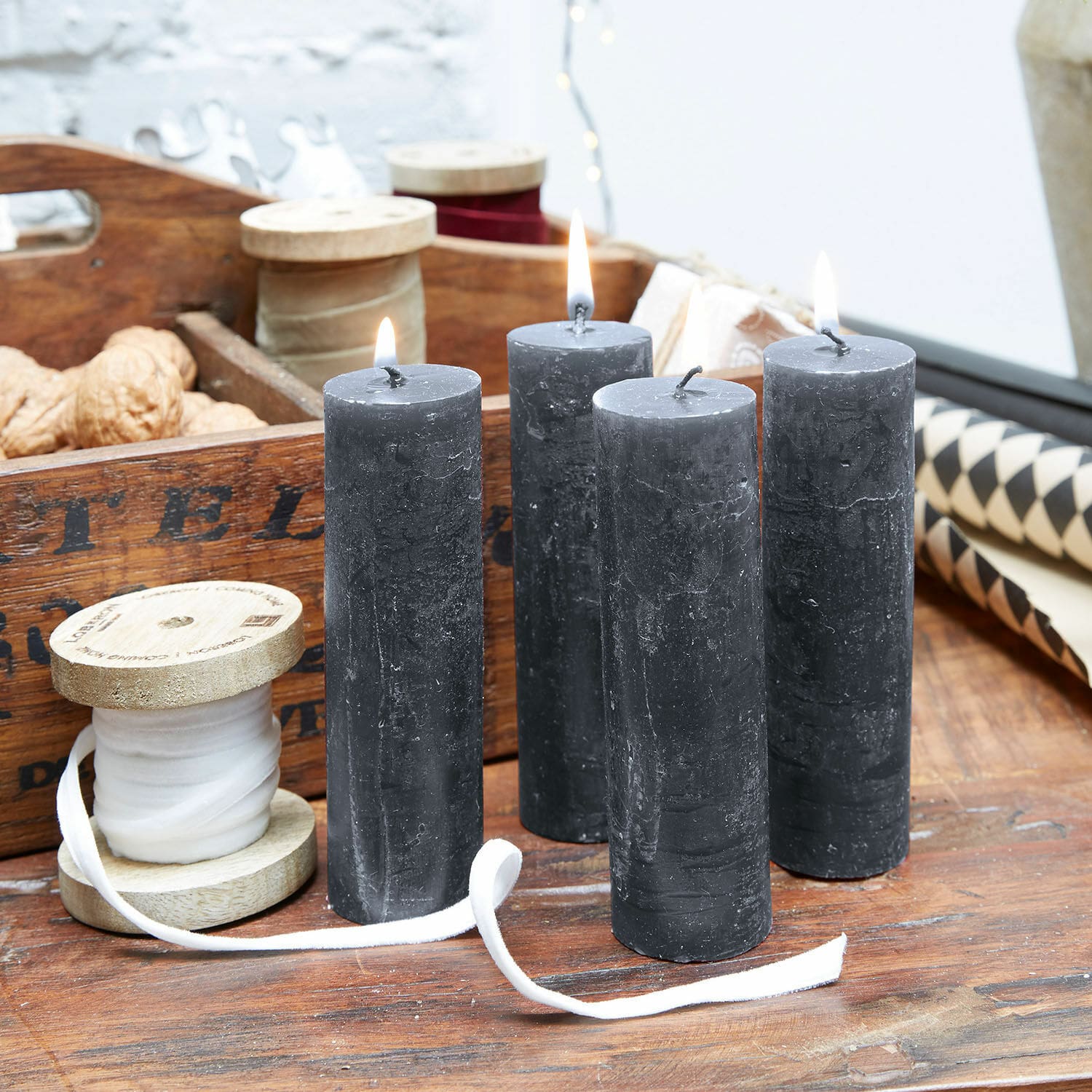 Lot de 4 bougies Muriel Quatre bougies noires en cire naturelle sur une table en bois avec bobines décoratives et noix