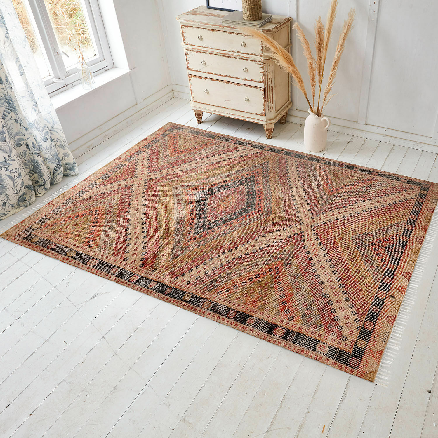 Tapis d’intérieur et d’extérieur Mildura Tapis à motif géométrique aux tons chauds rouge et beige sur un sol clair en bois