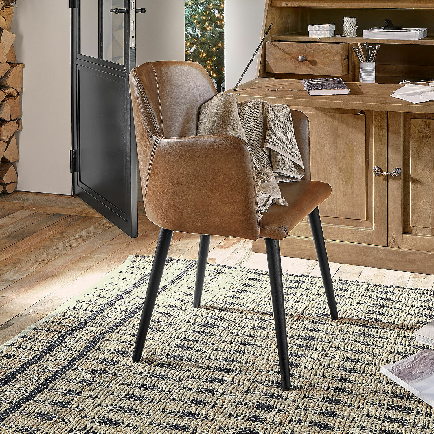 Chaise Zephiron Chaise marron en similicuir avec pieds noirs sur tapis dans un intérieur chaleureux avec meubles en bois