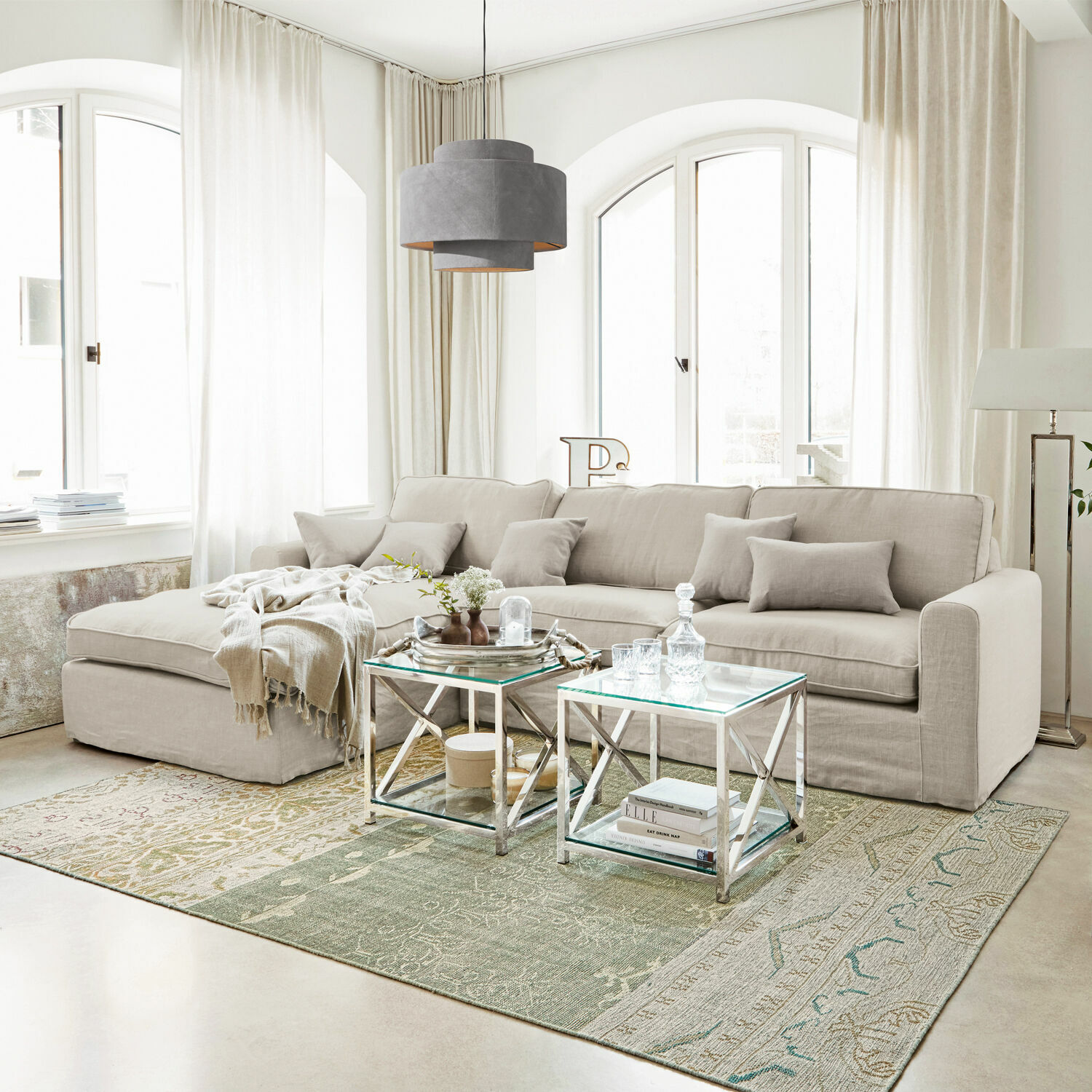 Canapé Seaford Grand canapé d'angle gris clair en tissu dans un salon moderne avec tables en métal et tapis