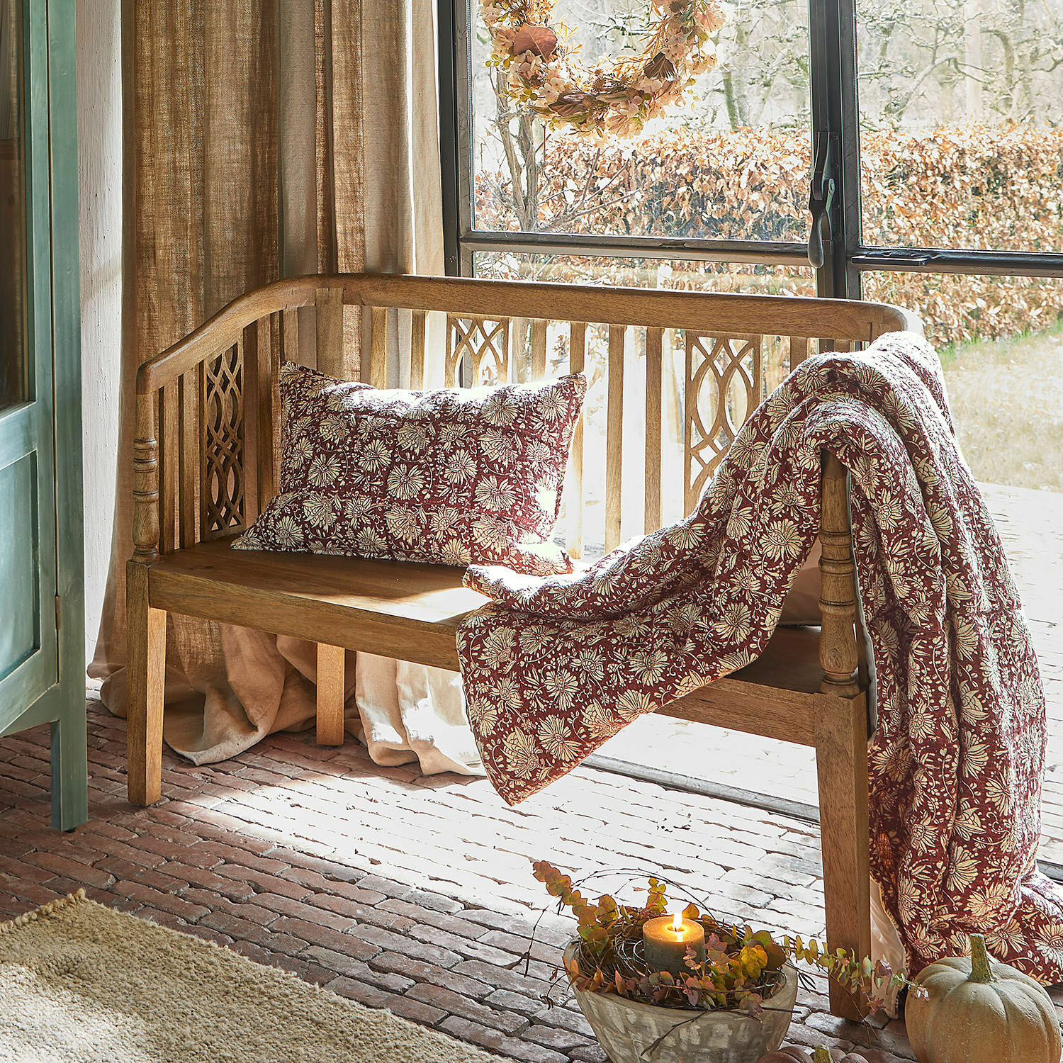 Banc Merveillant Banc en bois avec coussin et plaid à motif floral bordeaux et crème dans un intérieur chaleureux