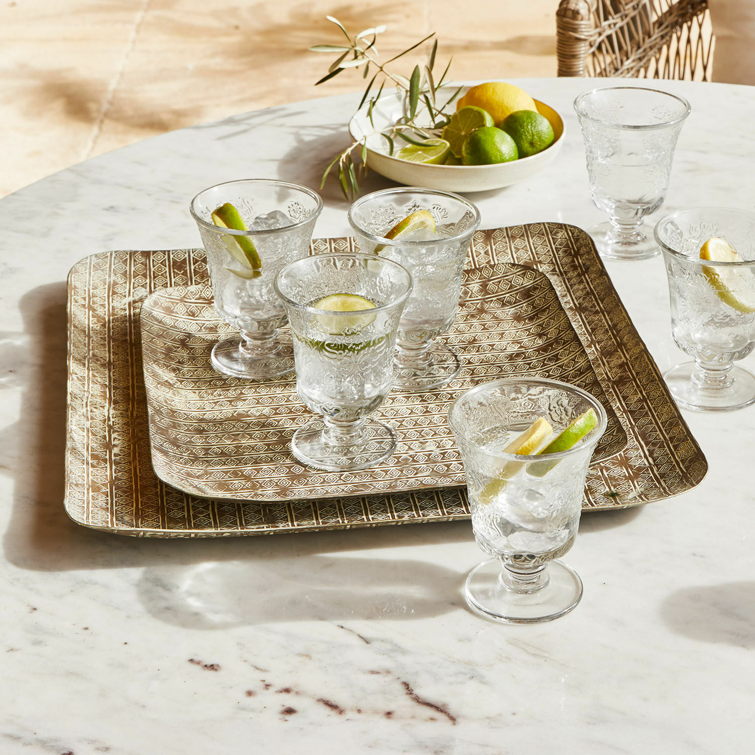 Lot de 2 plateaux Farouq Verres en verre gravé sur plateaux métalliques dorés posés sur une table en marbre