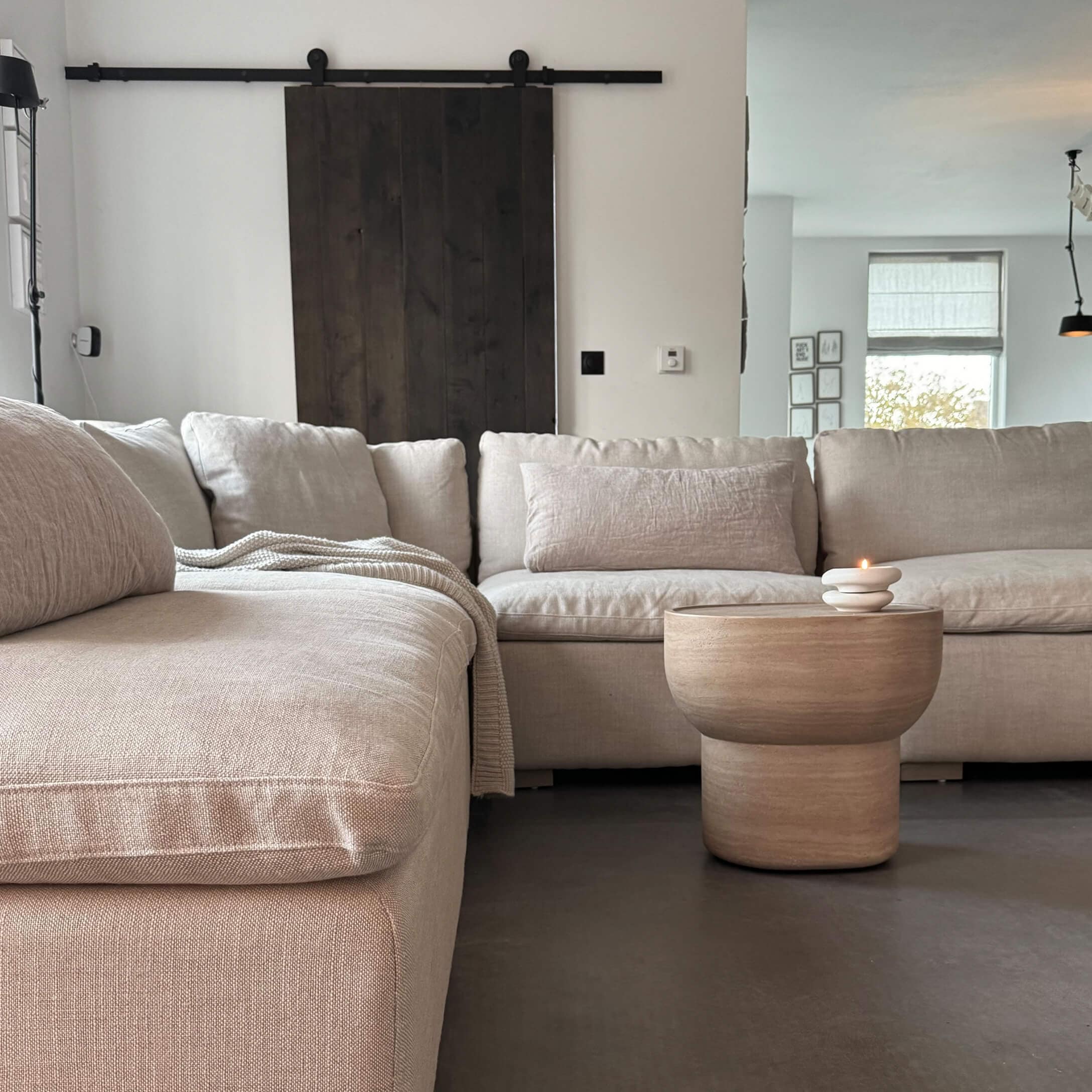 Canapé d'angle beige en tissu avec table basse en bois et bougie dans un salon moderne