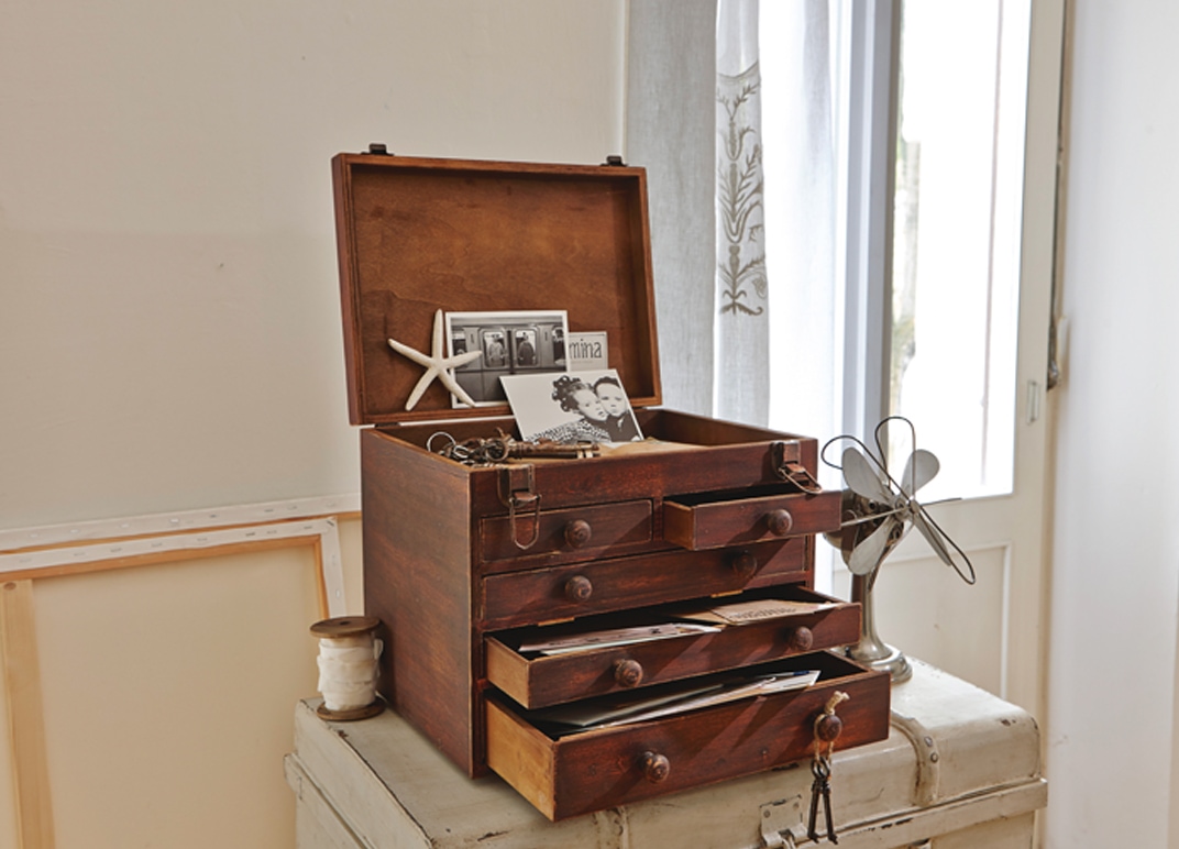 Boîte vintage en bois avec tiroirs ouverts contenant des photos et documents dans une pièce lumineuse