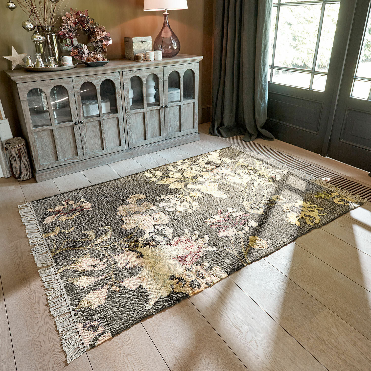 Tapis Yasirah Tapis à motif floral gris et crème sur un sol clair dans un salon lumineux