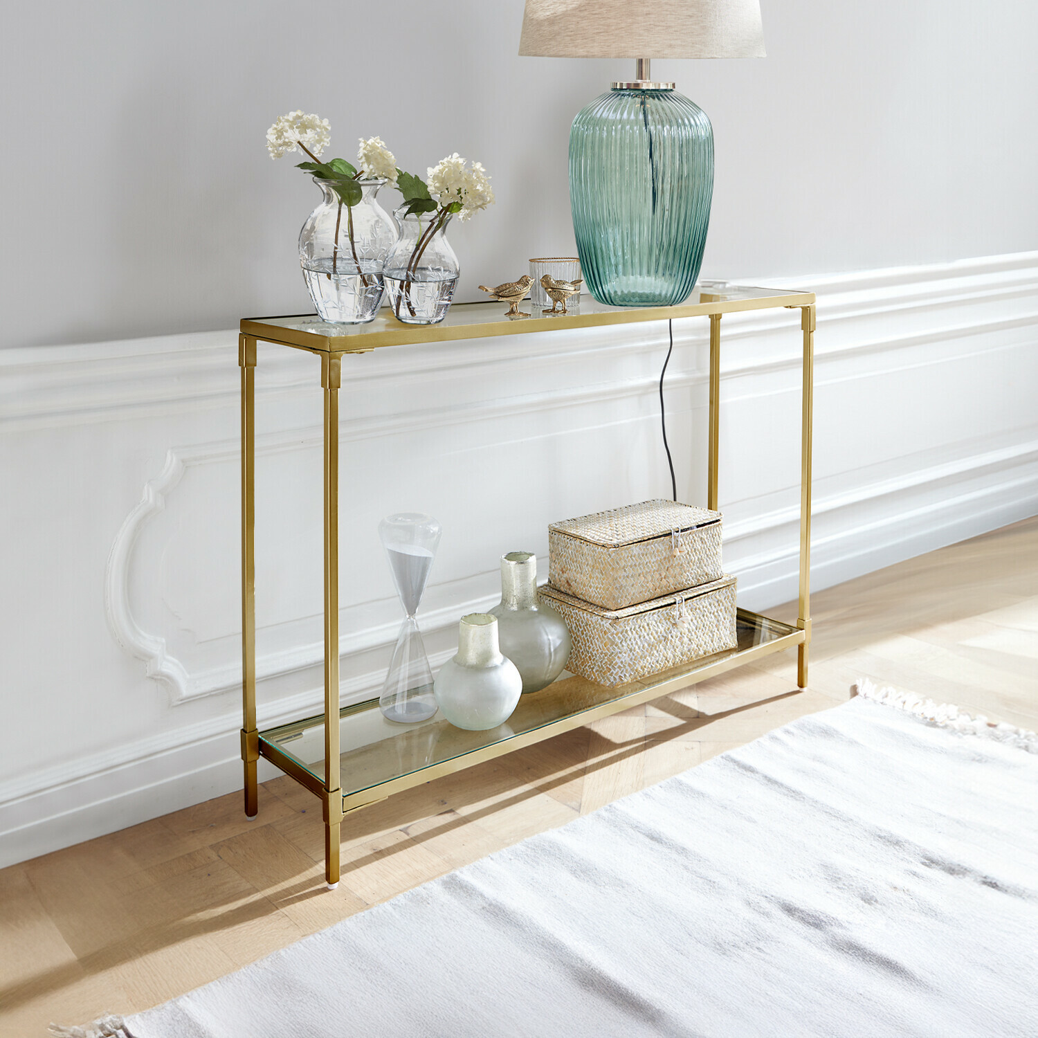 Console Ninove Console dorée en métal avec deux étagères en verre, décorée d'une lampe et de vases, style moderne