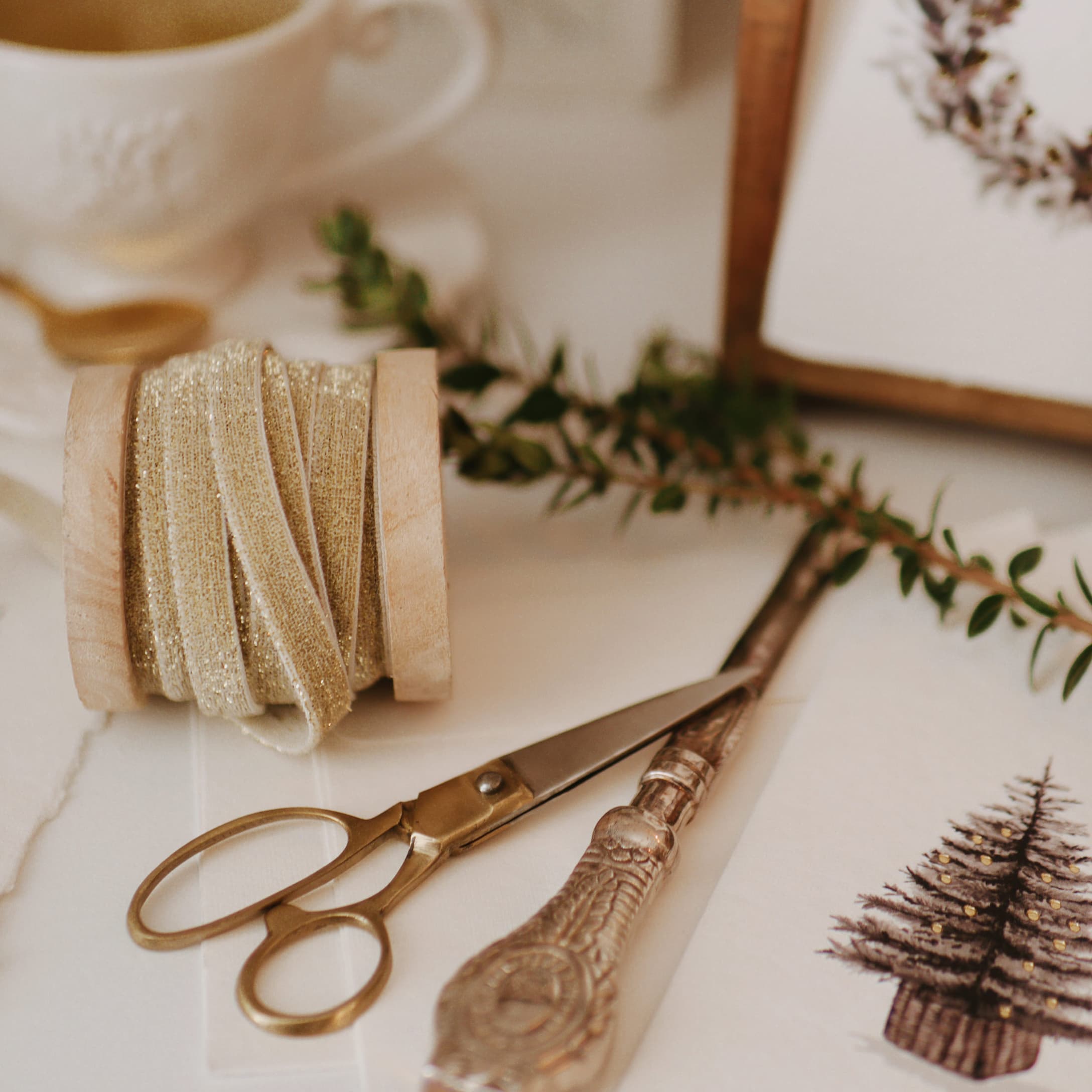 Ruban doré pailleté sur bobine en bois avec ciseaux et carte de Noël décorée d'un sapin
