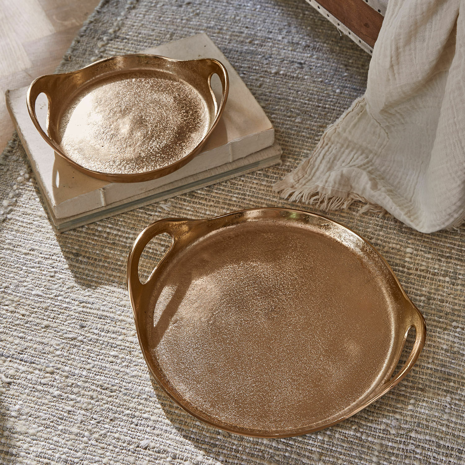 Lot de 2 plateaux Tiavela Ensemble de deux plateaux en cuivre avec poignées sur tapis textile et livres, décoration intérieure