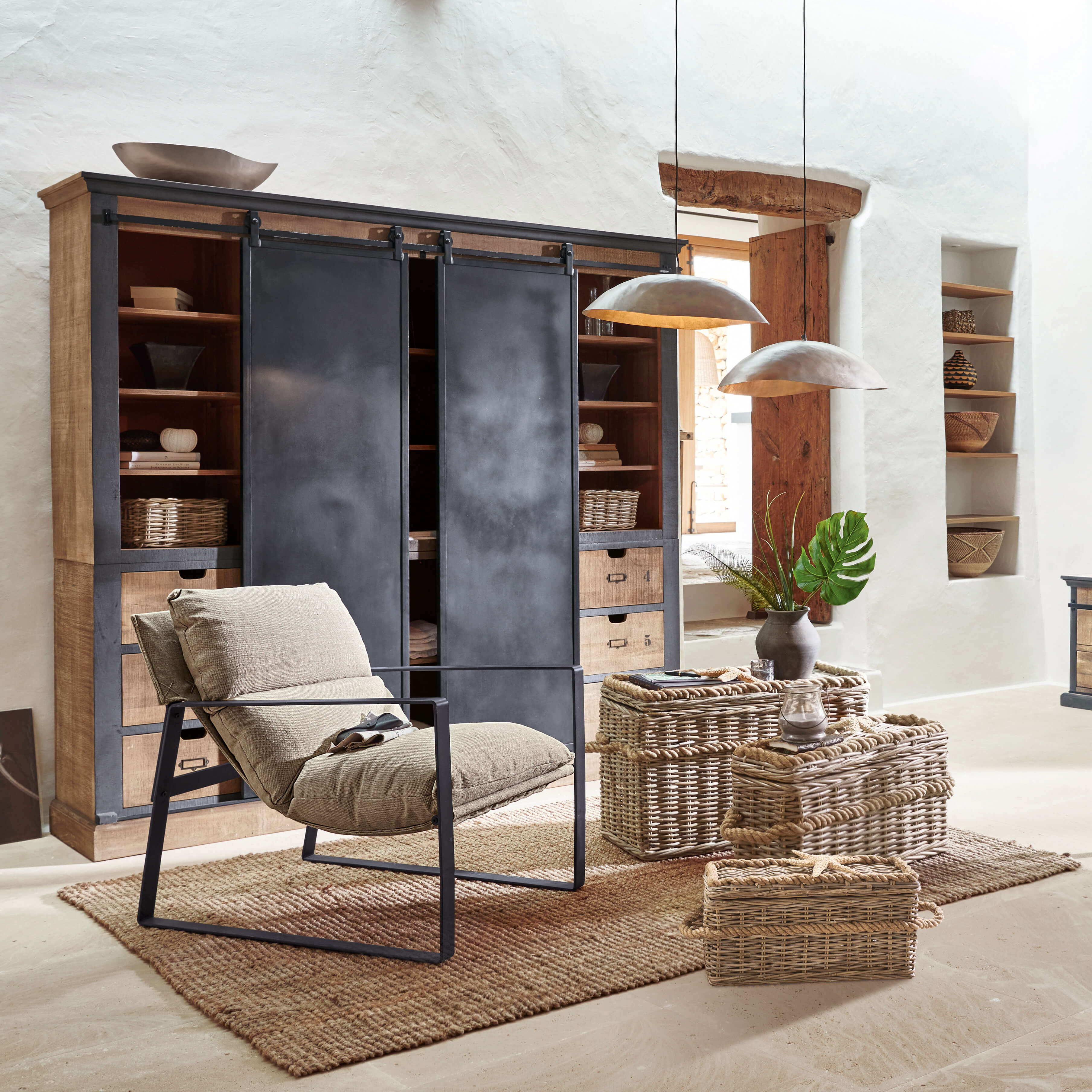 Fauteuil confortable en tissu beige avec cadre métallique dans un salon rustique avec paniers en osier